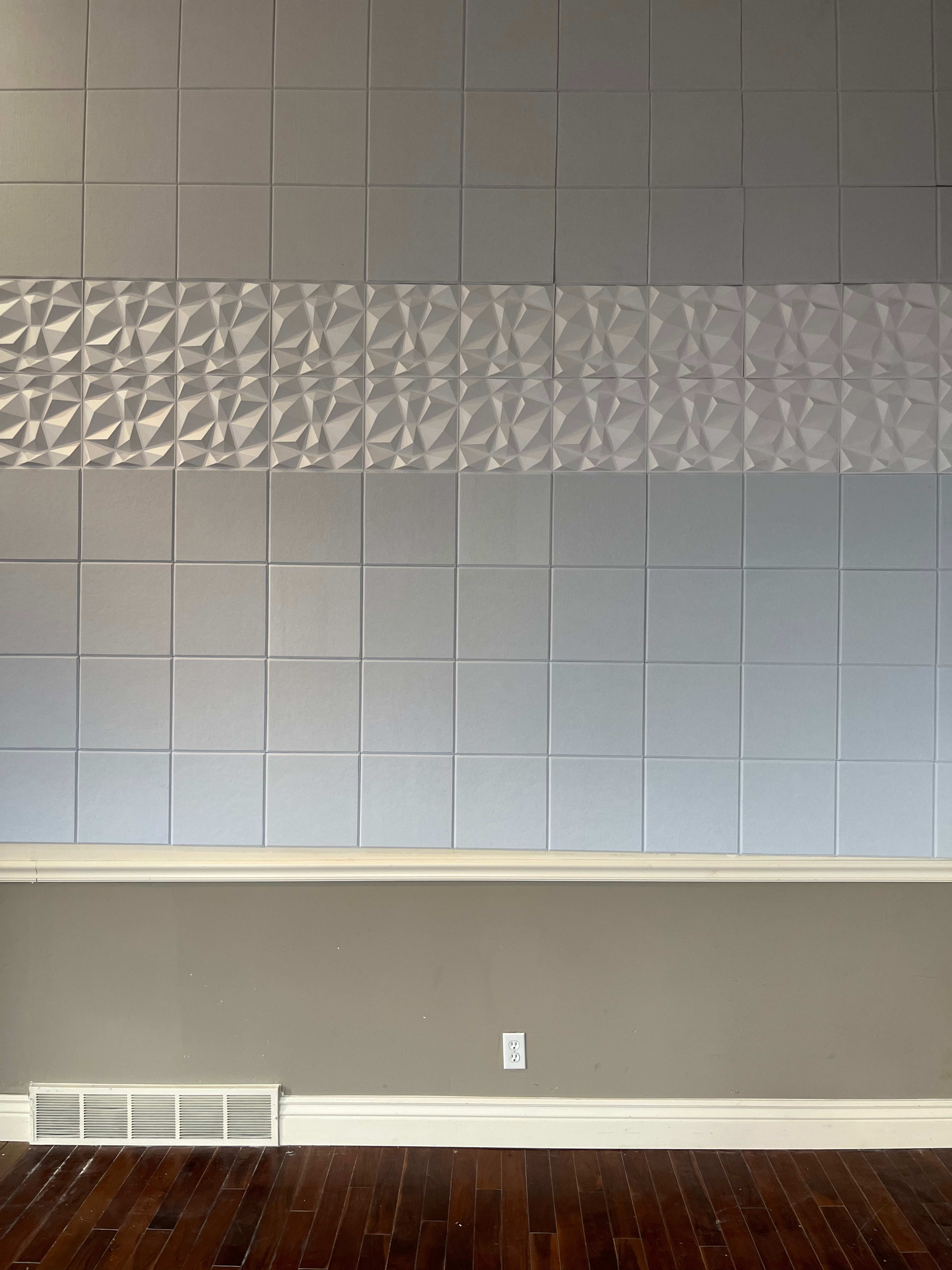 The image shows a wall divided into two sections, one featuring textured, three-dimensional tiles and the other composed of flat, square tiles.
