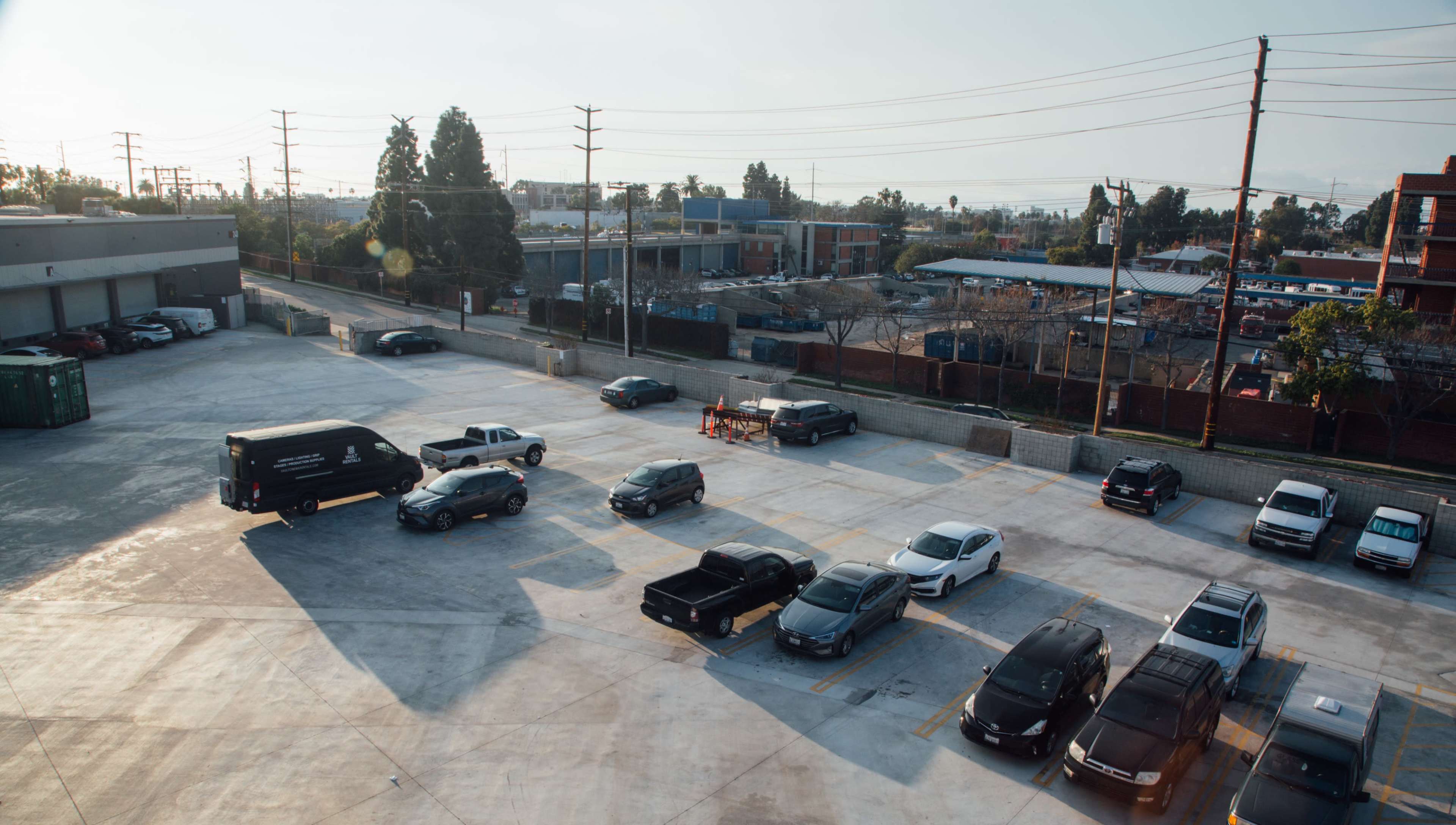 The image shows a parking lot with several cars parked, surrounded by construction and commercial buildings in the background.