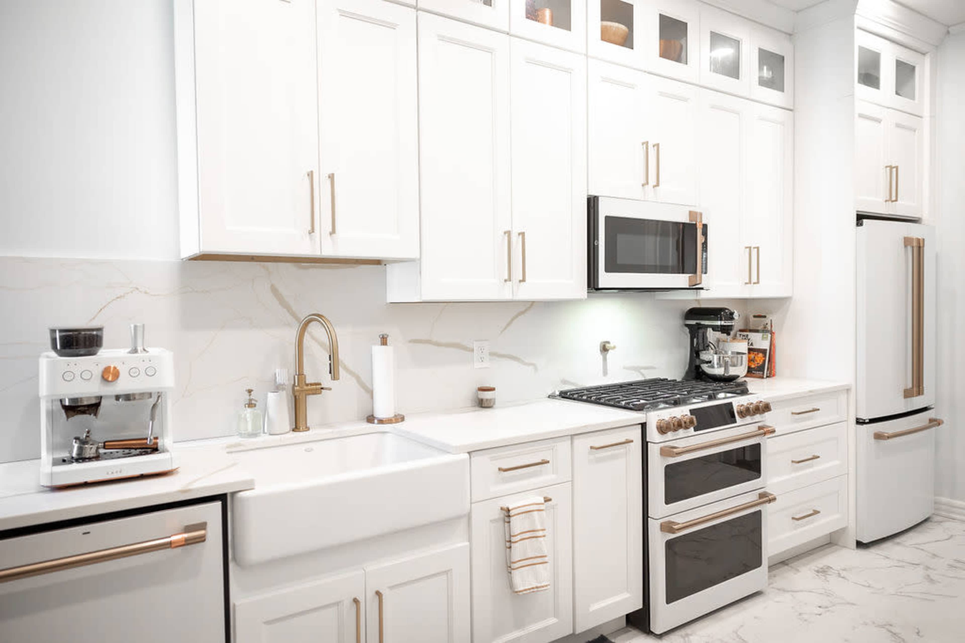 A modern kitchen featuring white cabinets, stainless steel appliances, and a large farmhouse sink.