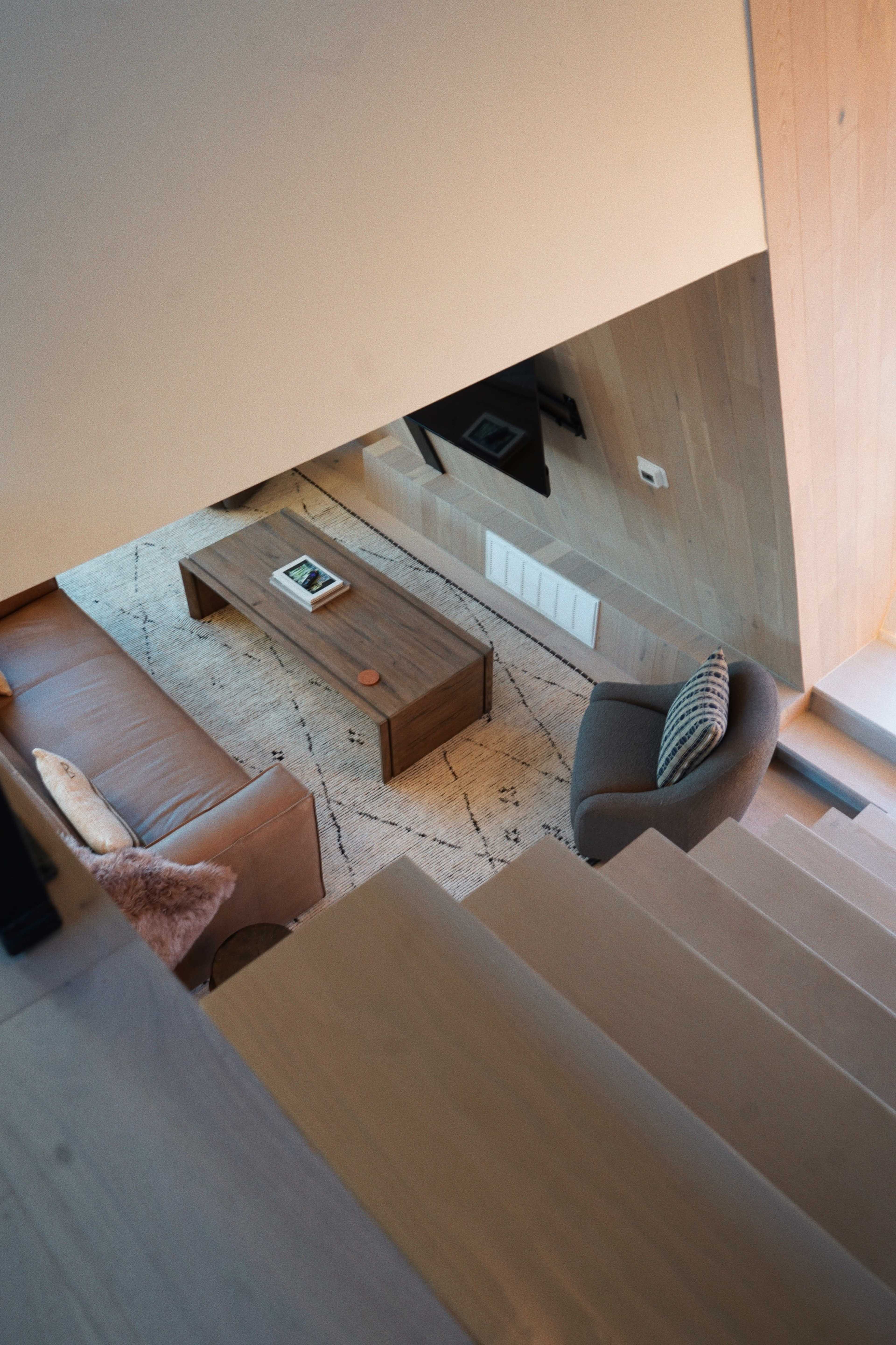 A staircase descending into a modern living room with a wooden coffee table, a couch, and a rug.