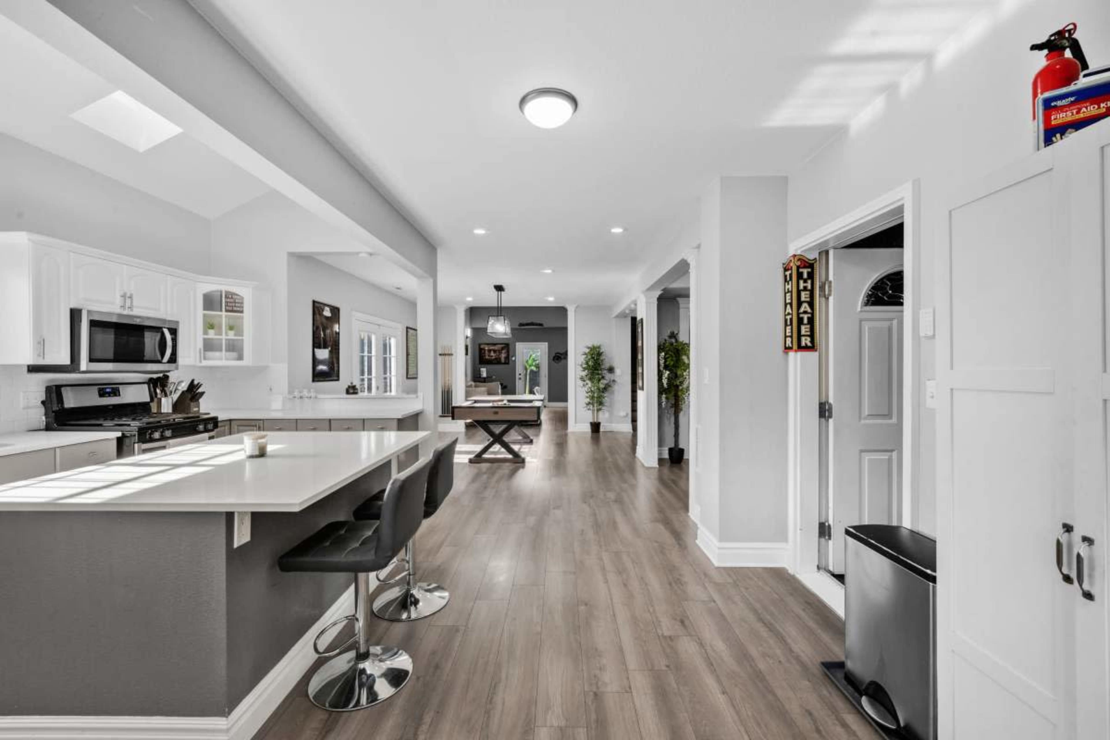 A spacious, modern kitchen and dining area with a central island, sleek bar stools, and wood flooring.