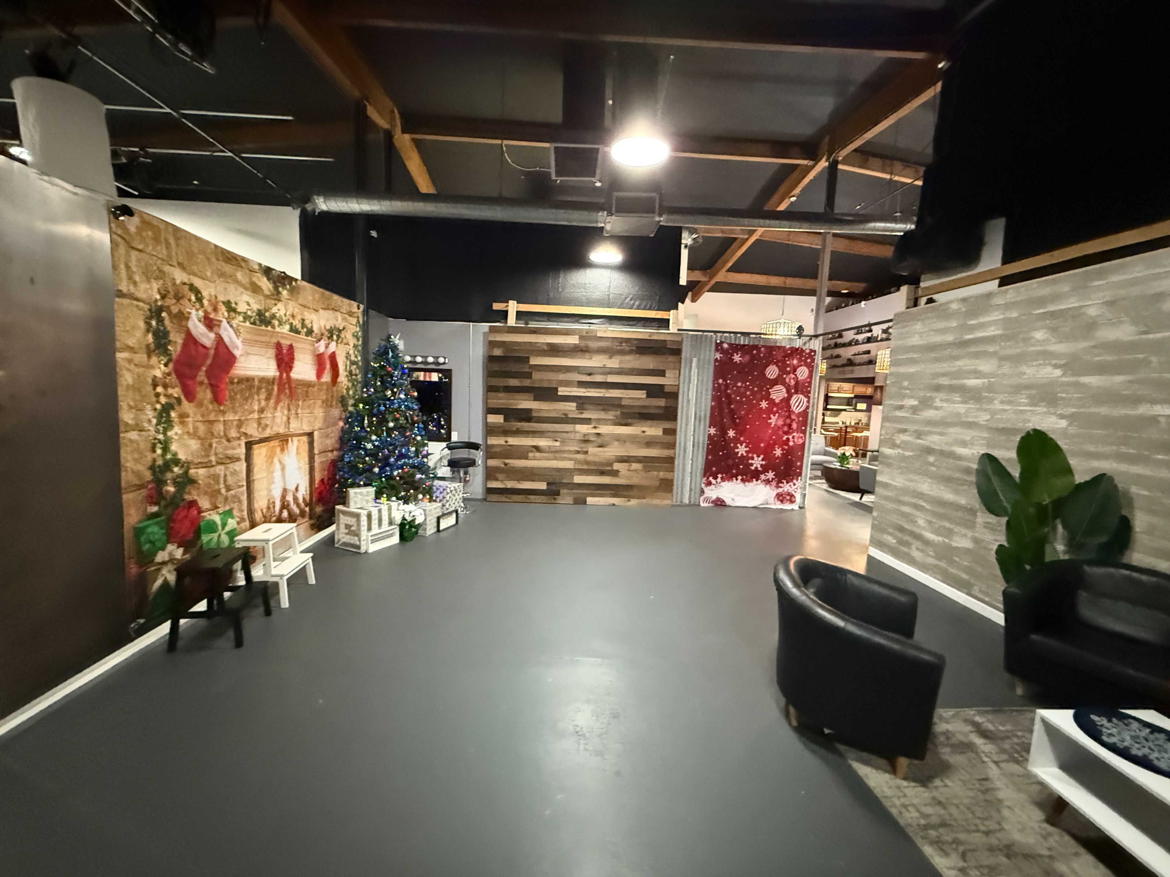 The image shows a spacious room with decorated walls, including a fireplace scene with stockings, a Christmas tree, and various seating areas.