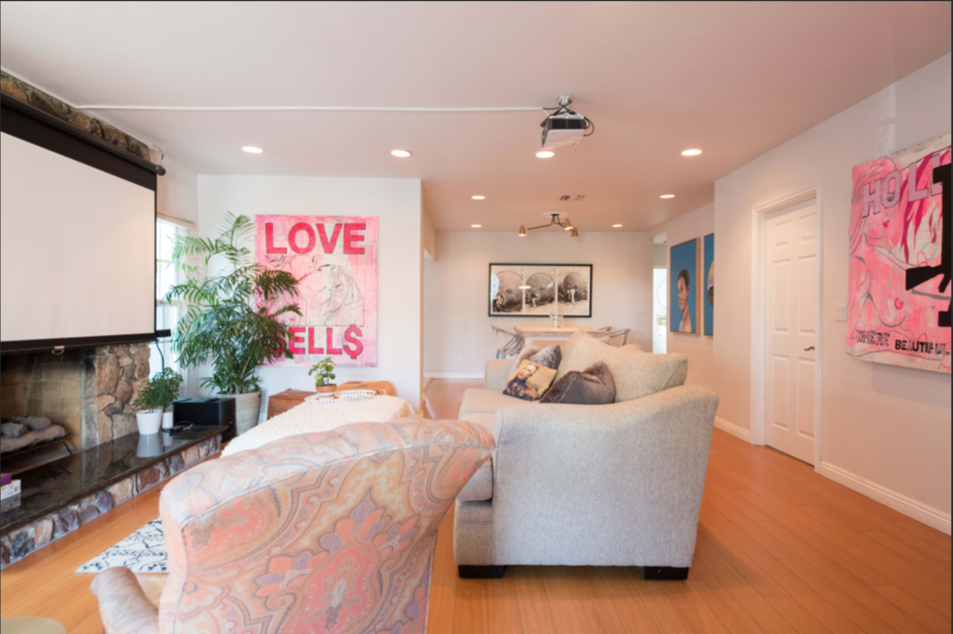 A modern living room with a sofa, a projector screen, and artwork on the walls.