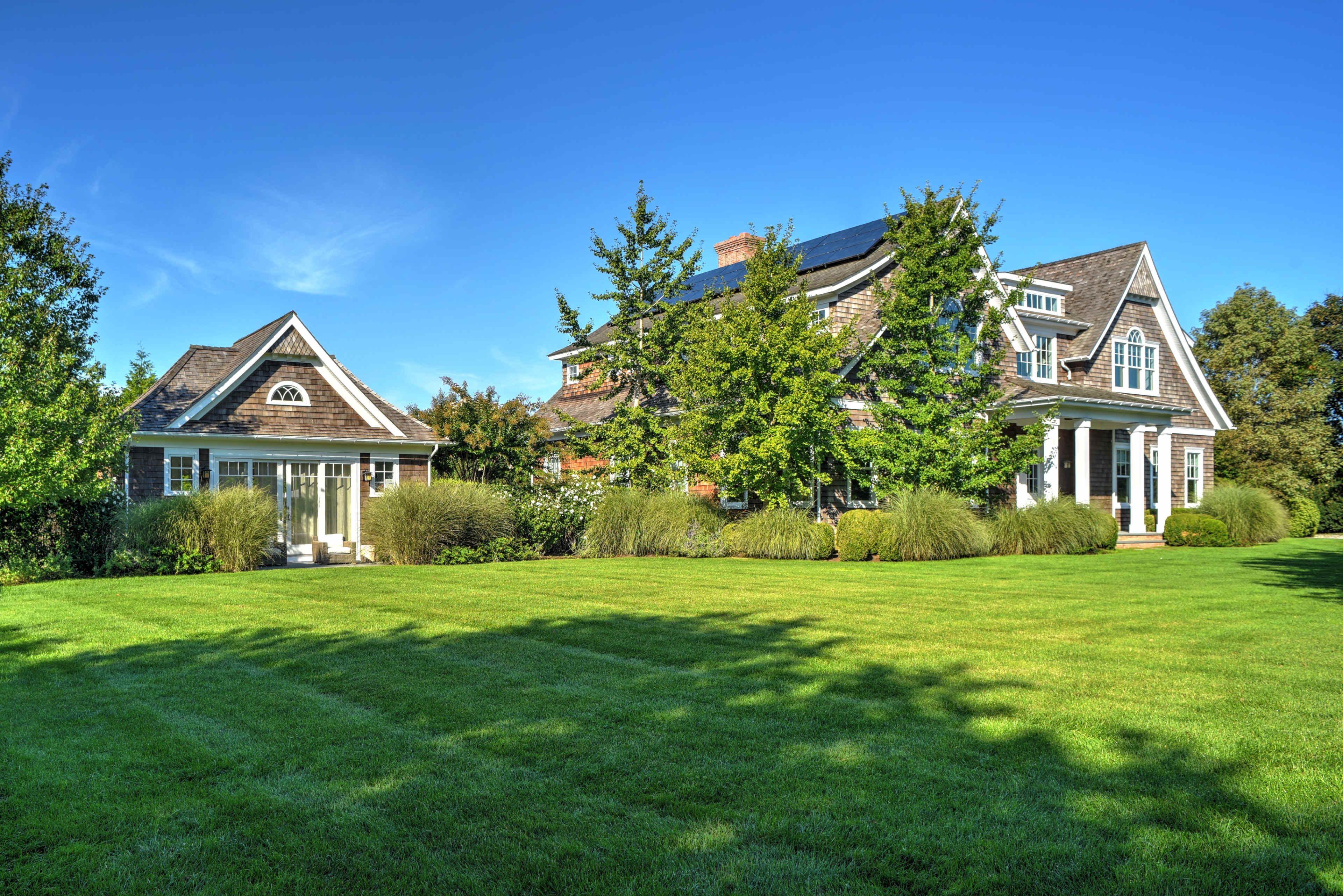 A large house with multiple gables surrounded by well-maintained lawns and trees.