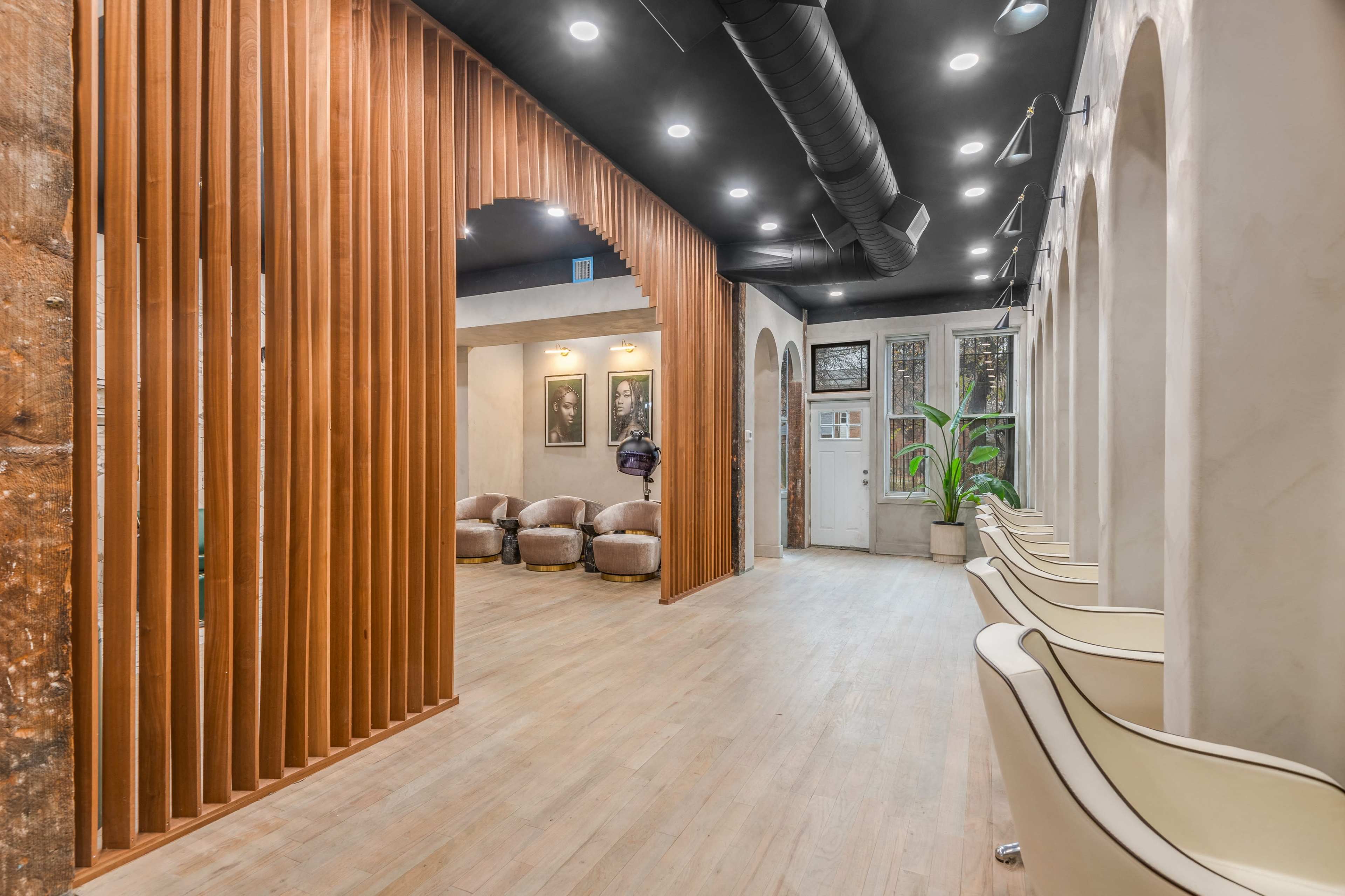 The image shows a modern interior space with wooden partitions, seating areas, and large windows.