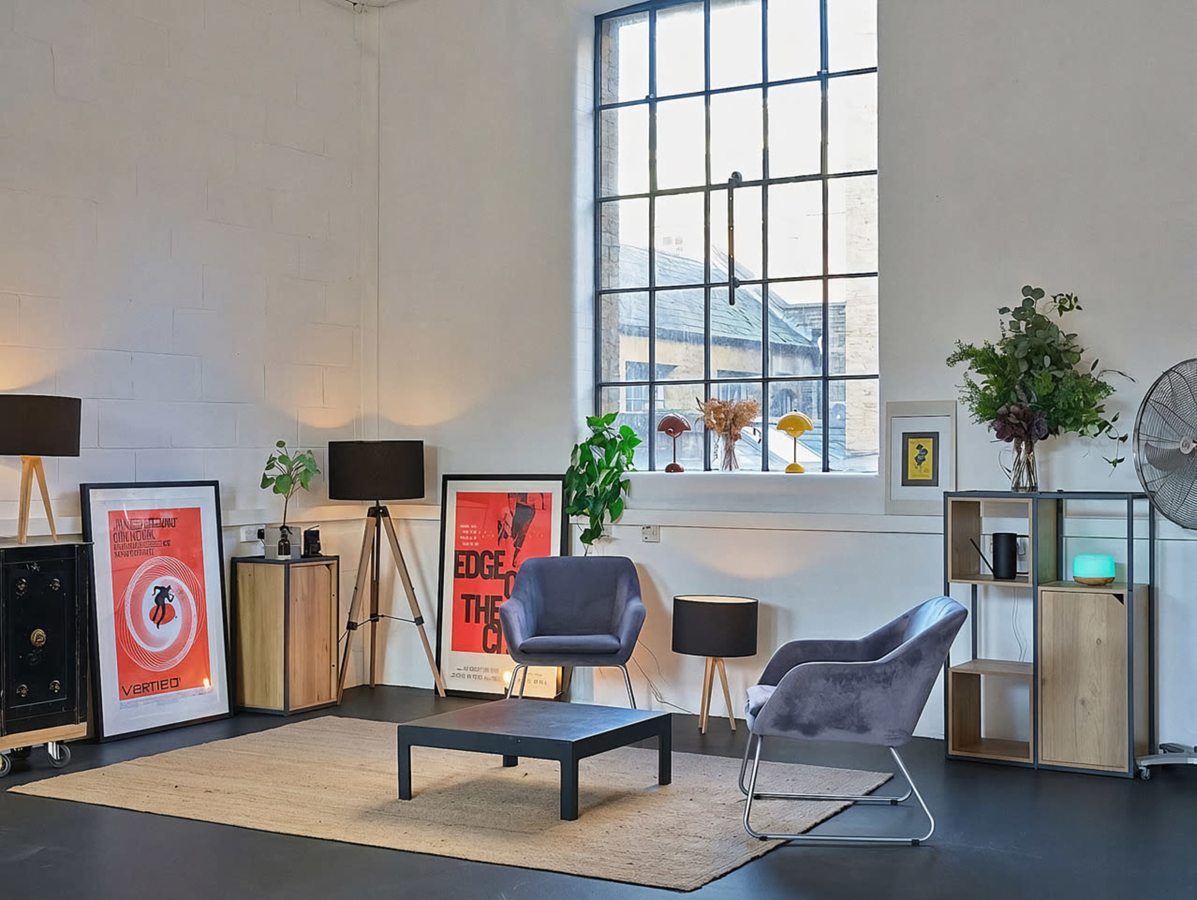 The image features a modern living space with a grey armchair, a low black table, and framed artwork on the walls, illuminated by soft lighting from floor lamps.