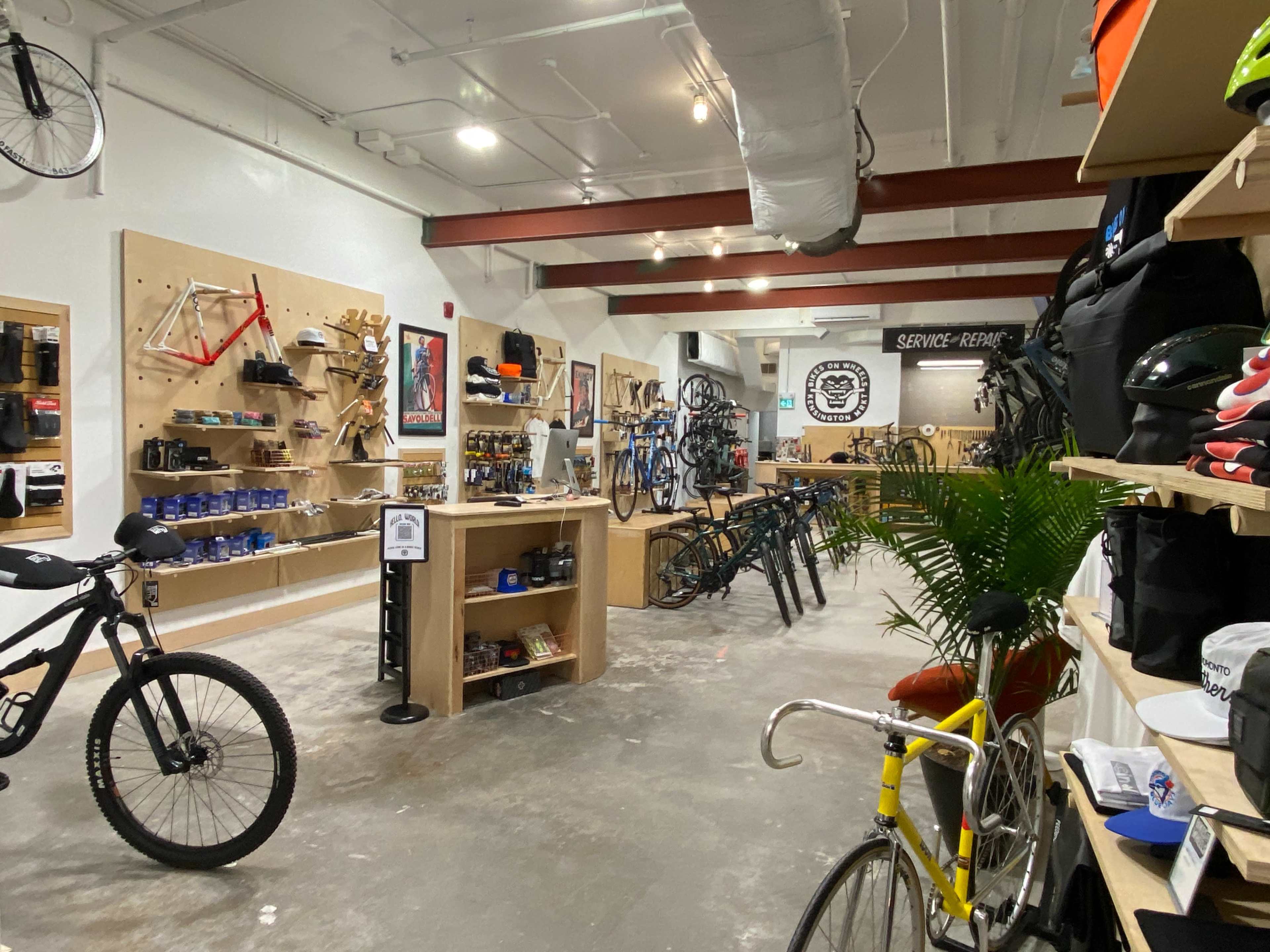 The image shows a bicycle shop interior with various bikes, accessories, and display shelves along the walls.