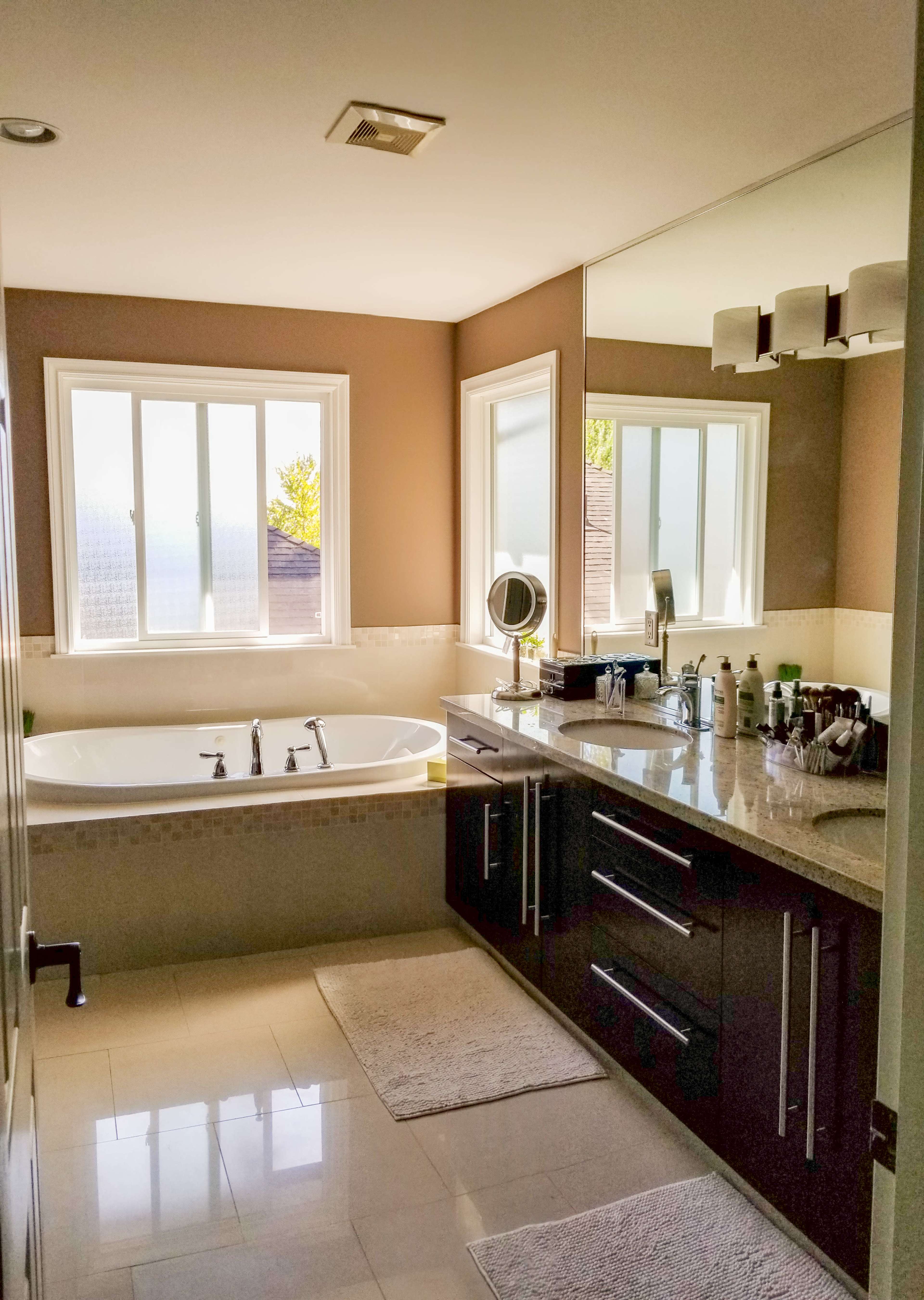 A modern bathroom featuring a large bathtub, a double vanity with a sink, and a large mirror above the countertop.