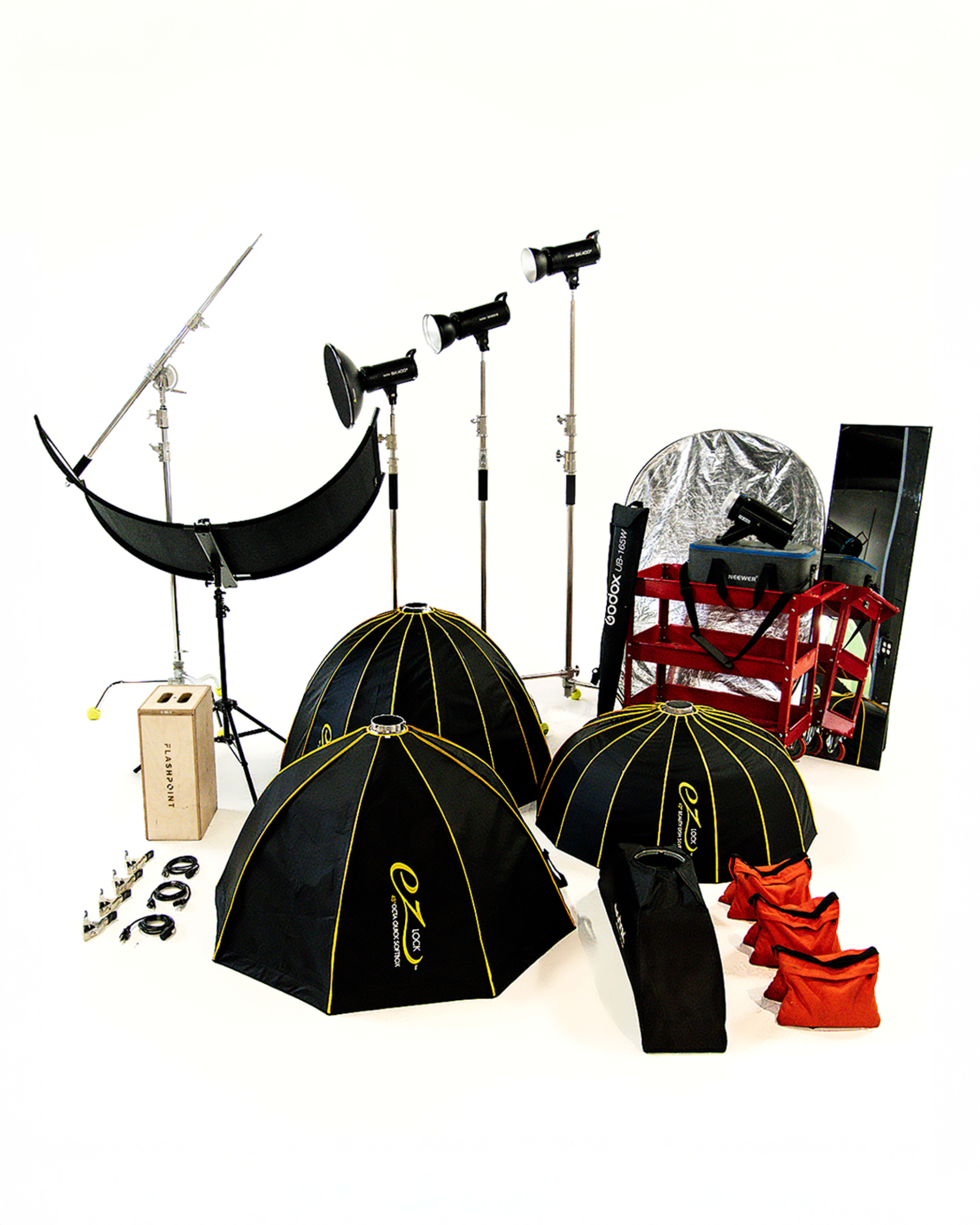 The image displays a collection of photography equipment, including light umbrellas, softboxes, light stands, and various accessories arranged on a white background.