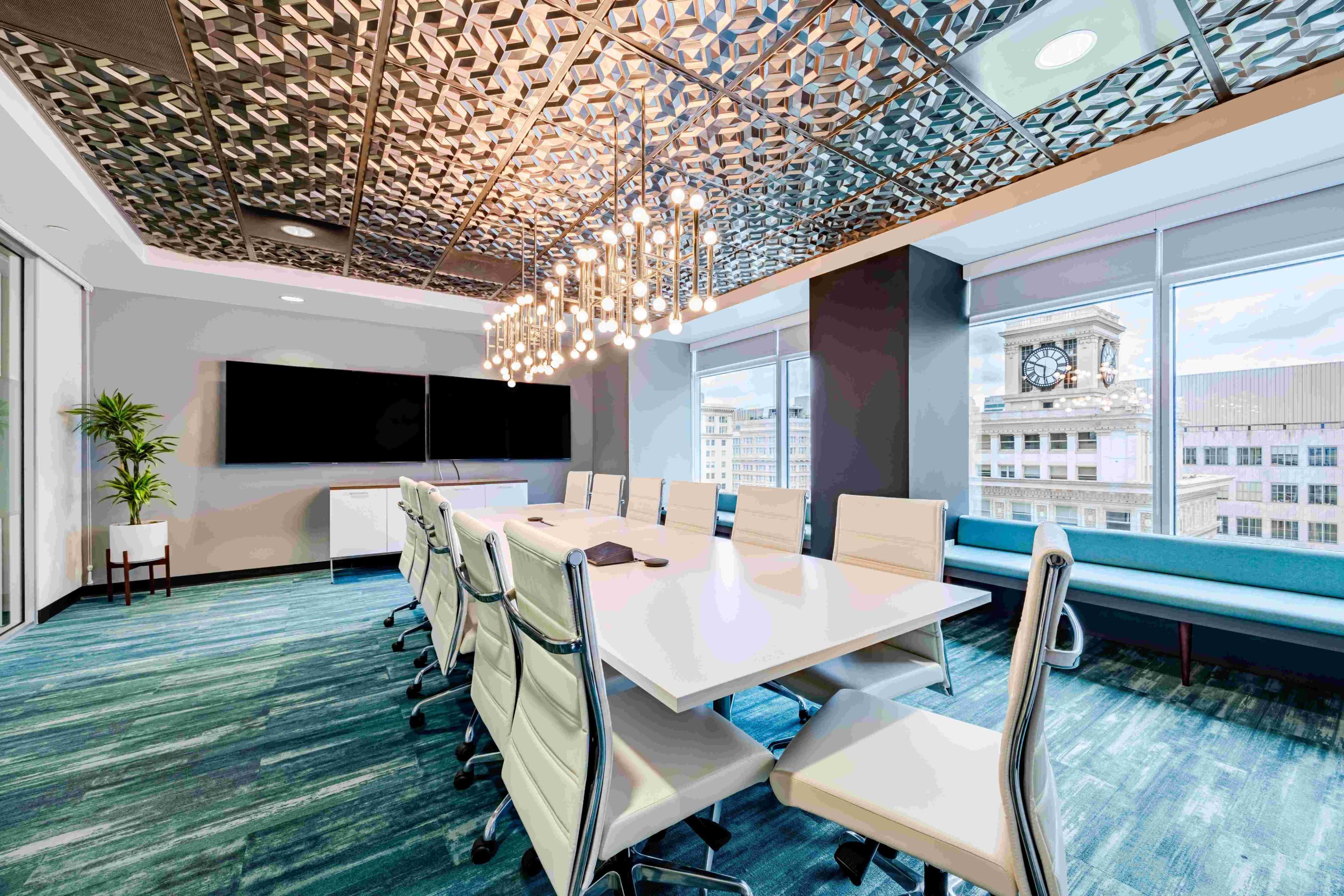 A modern conference room features a long white table surrounded by ergonomic chairs, a decorative ceiling, and large windows with a city view.