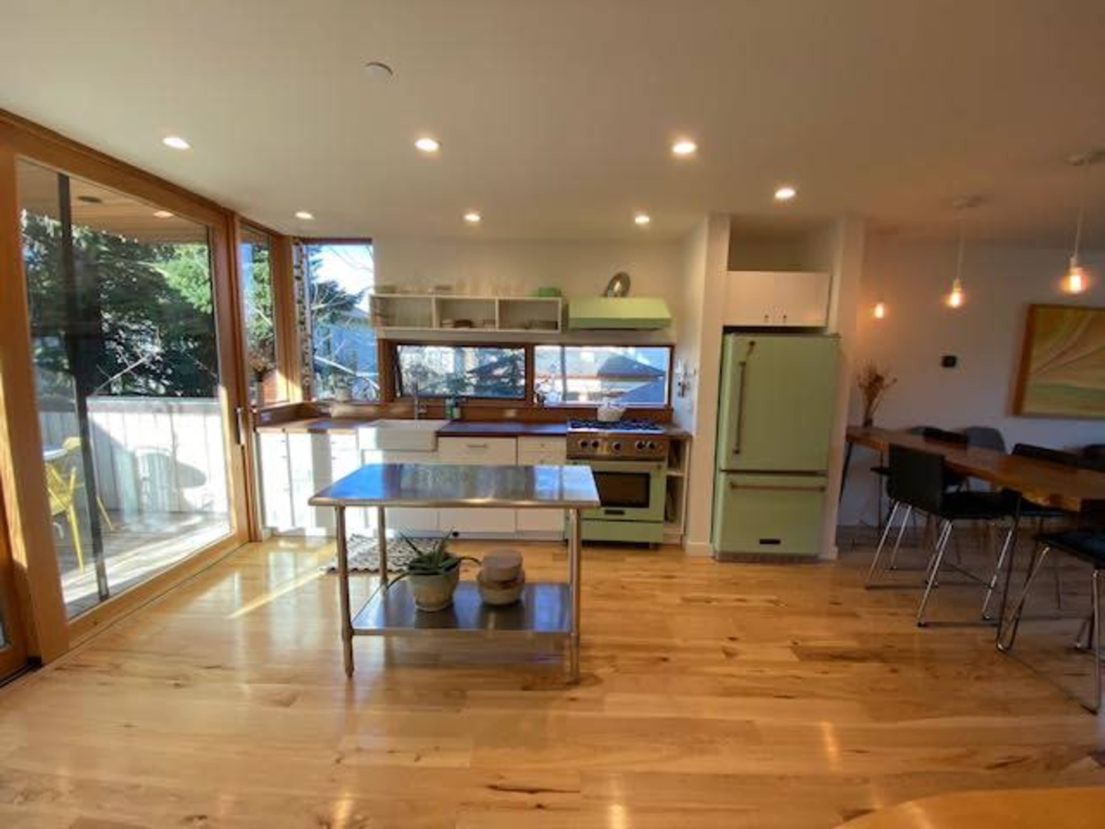 A modern kitchen with green appliances, wooden cabinets, and a dining area with a table and chairs.