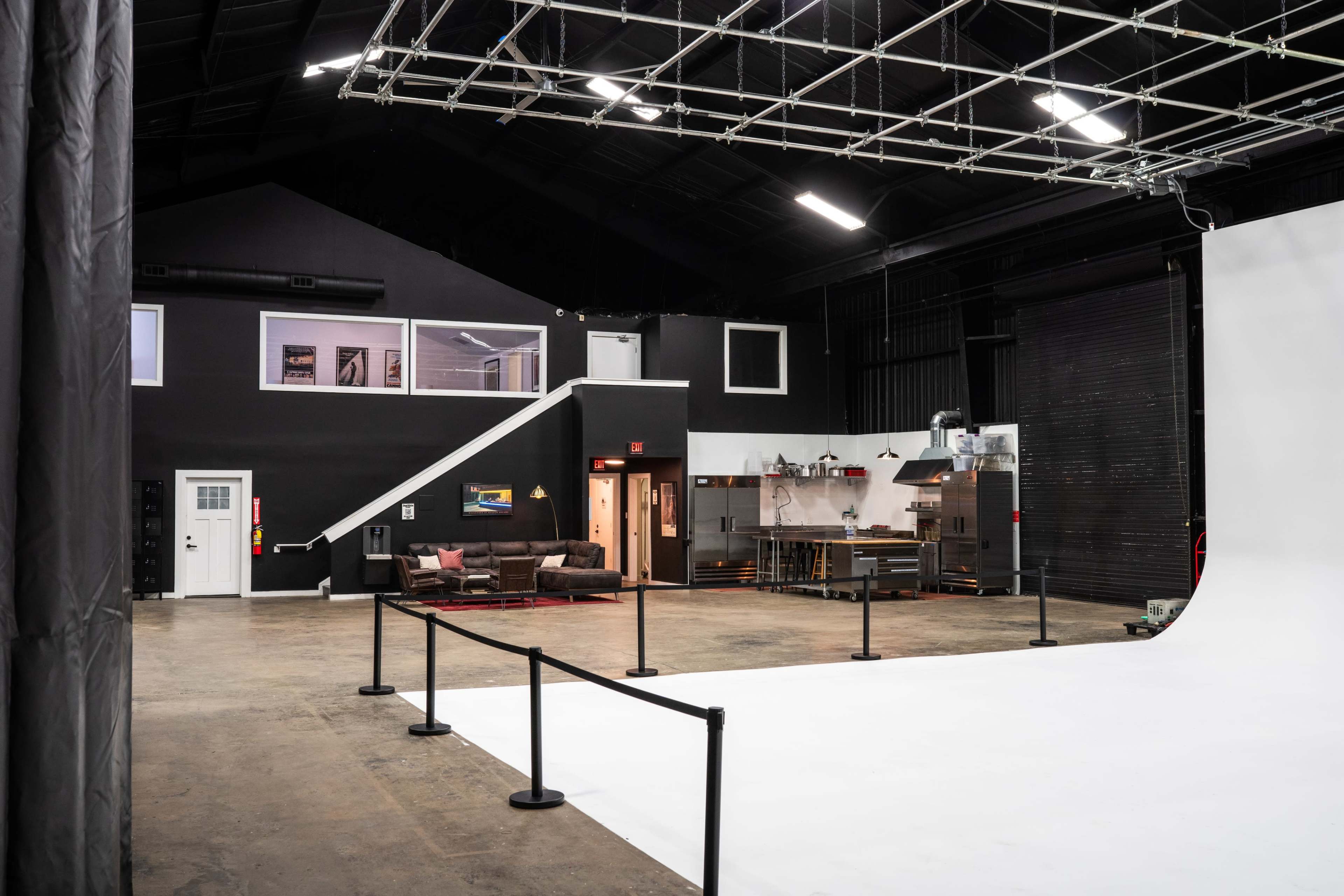 A spacious studio with a white backdrop, a lounge area on the left, and a kitchen space in the background.