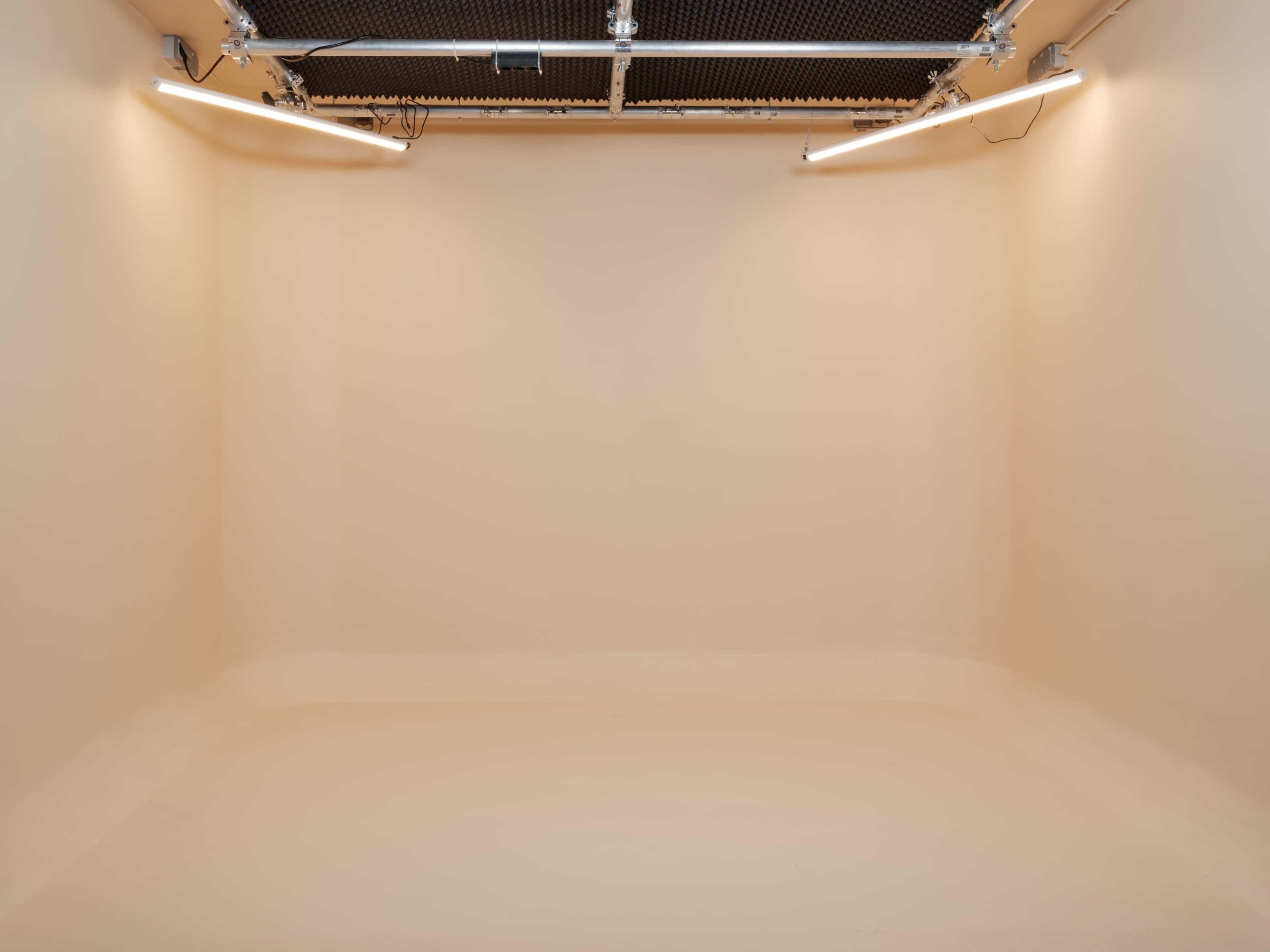 The image shows a clean, empty room with beige walls and ceiling lights.