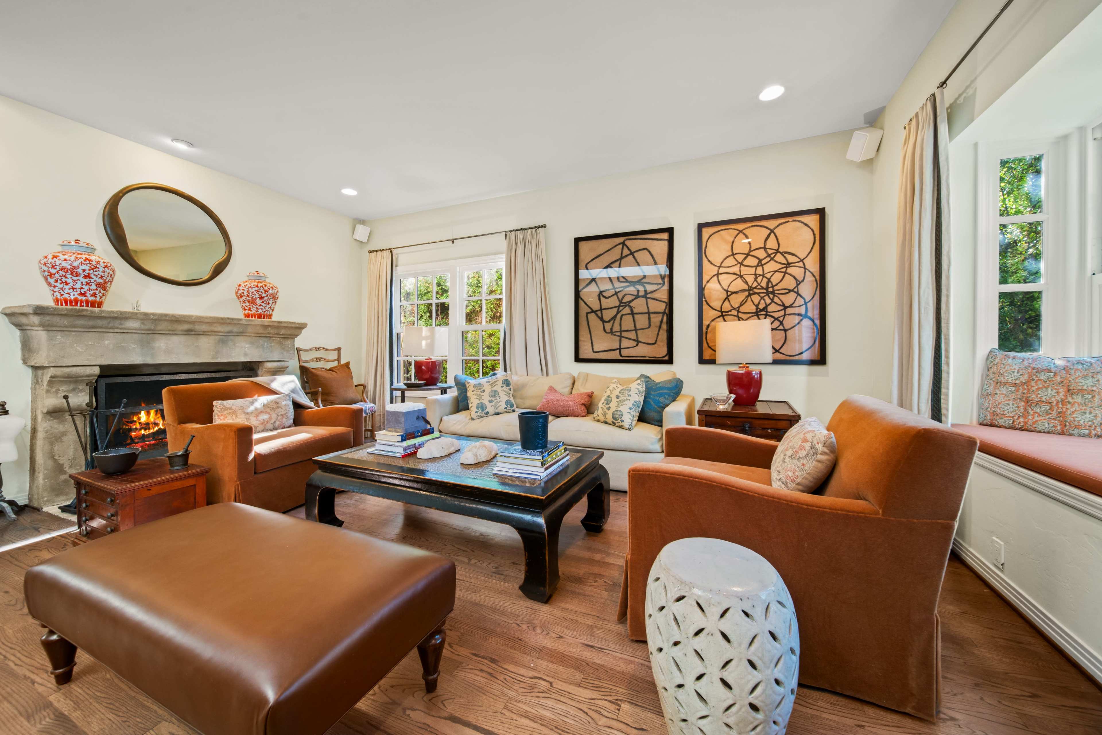The living room features a central seating area with a sofa and chairs arranged around a coffee table, complemented by decorative art and a fireplace.