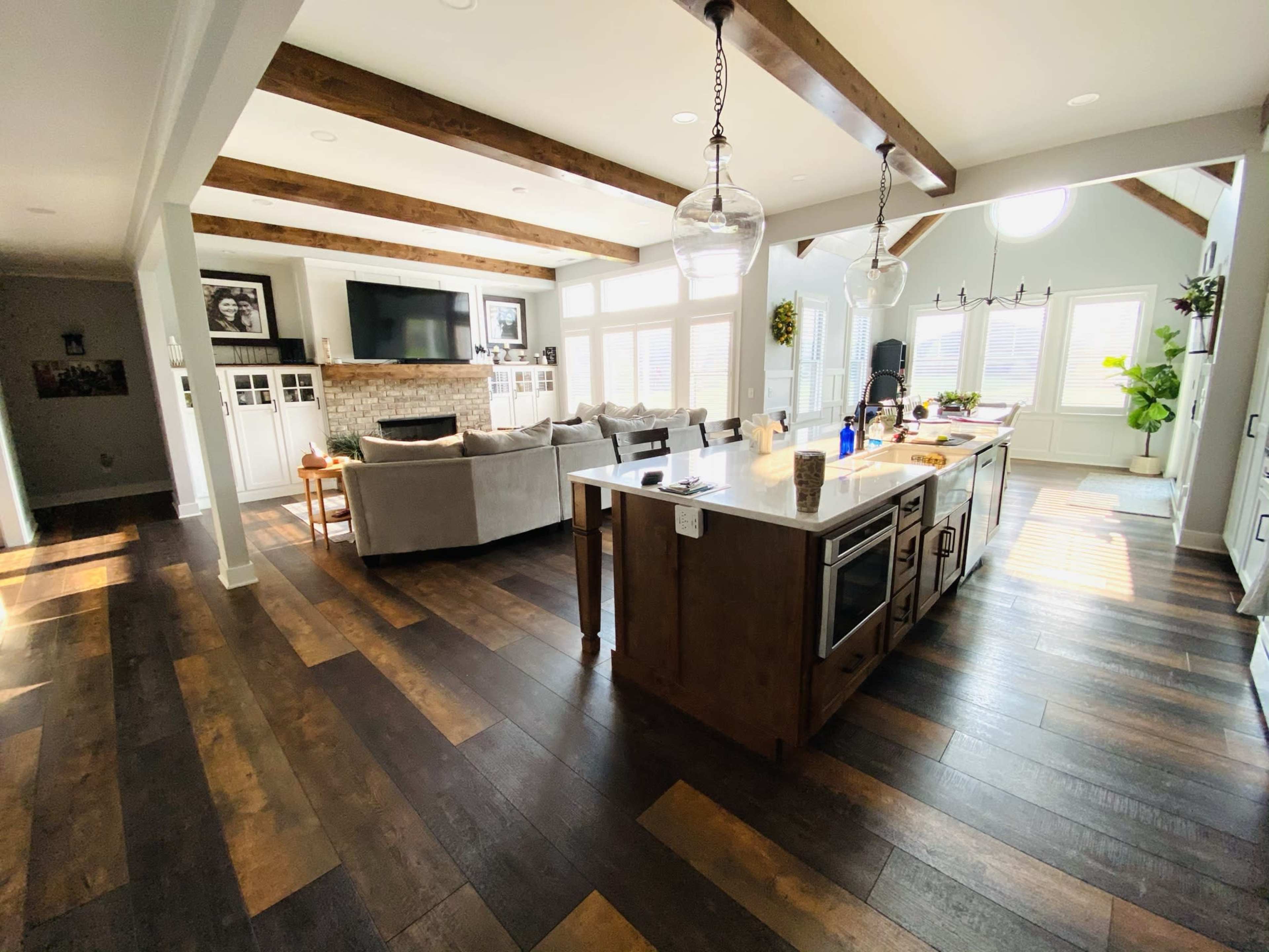 A spacious living area features a modern kitchen island, a seating area with a sectional sofa, and large windows allowing natural light to fill the room.