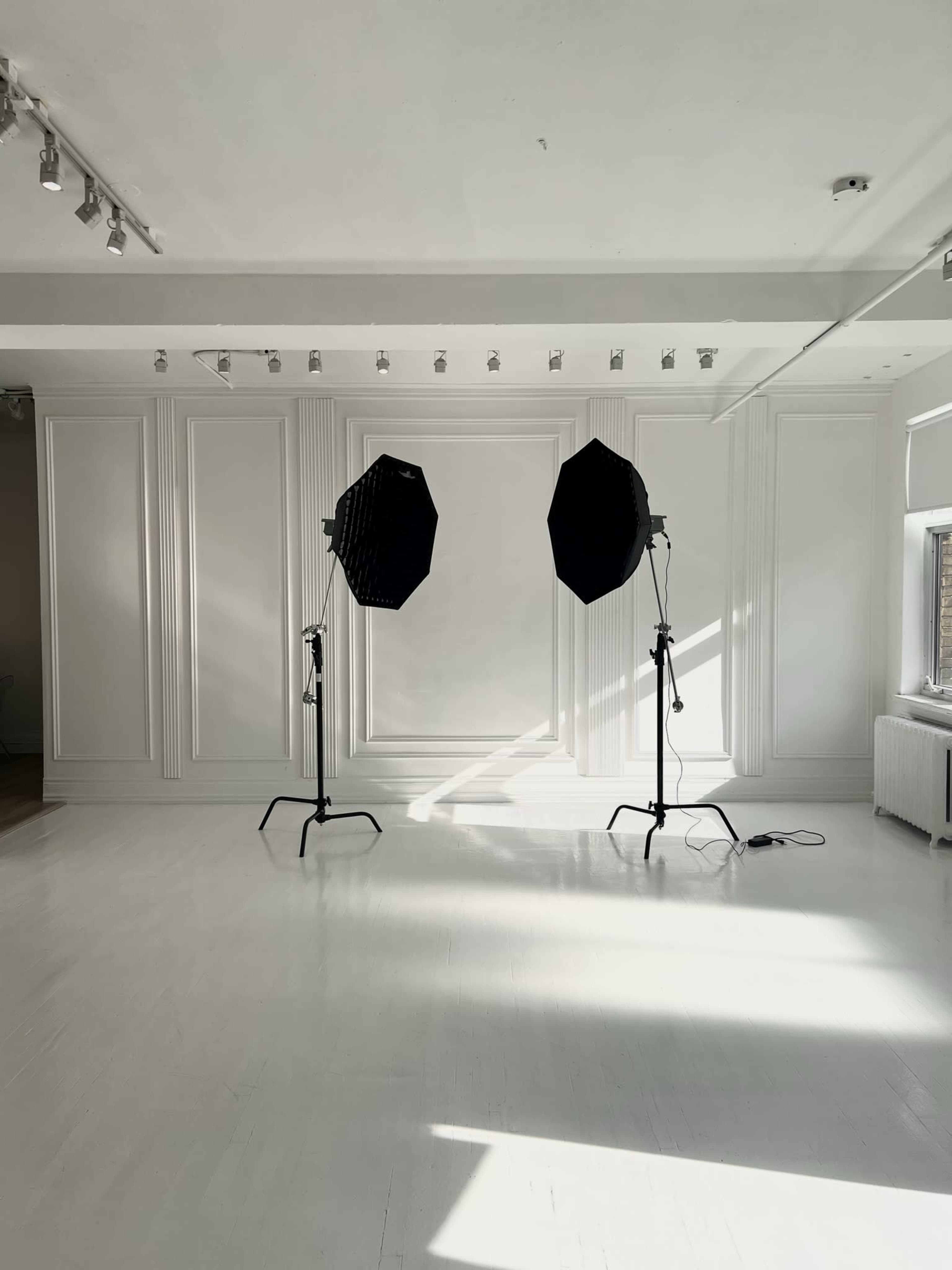 A bright, empty studio space with two large softbox lights positioned on stands.