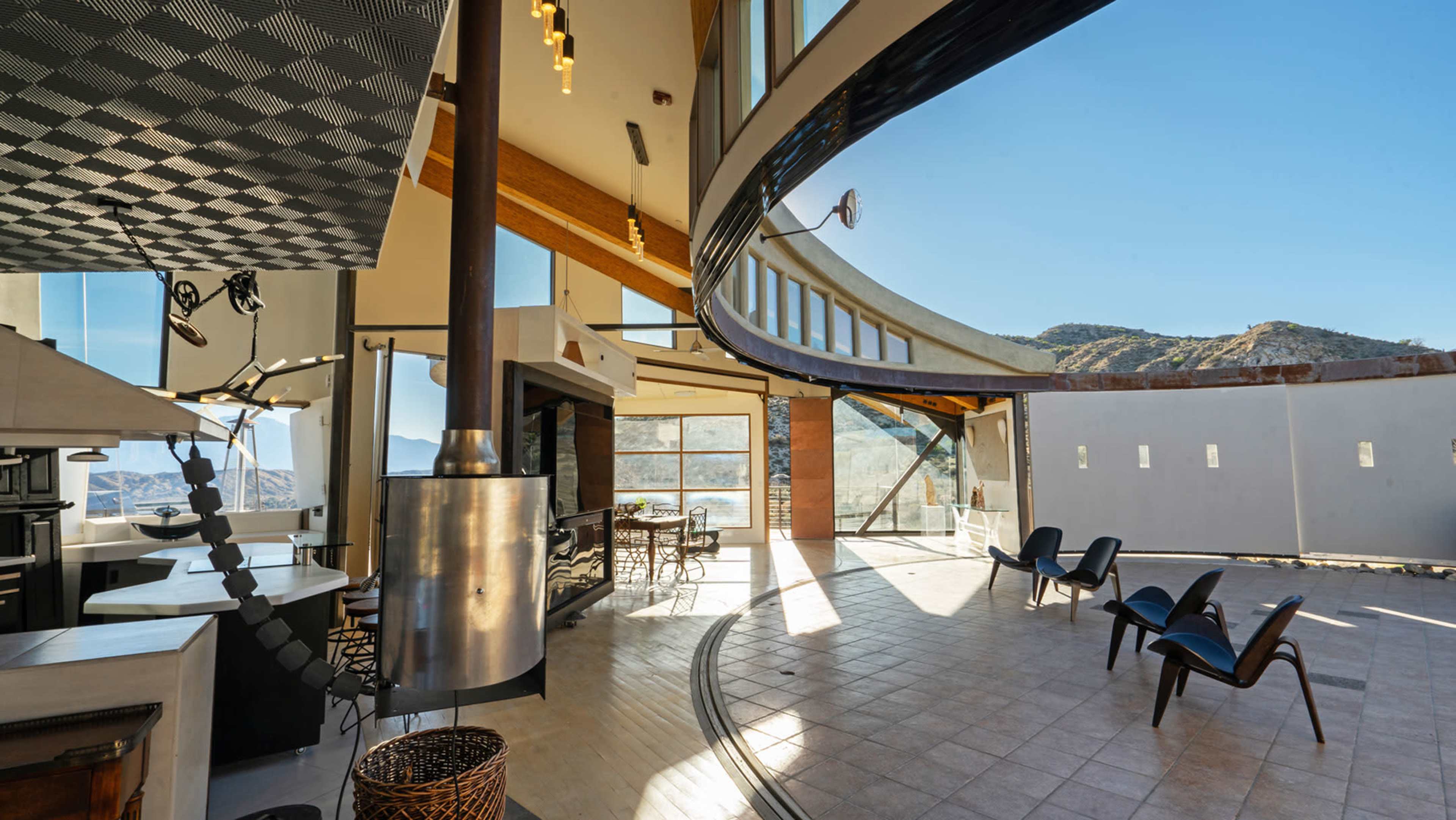 A modern, open-concept interior with large windows that provide a view of mountainous terrain.