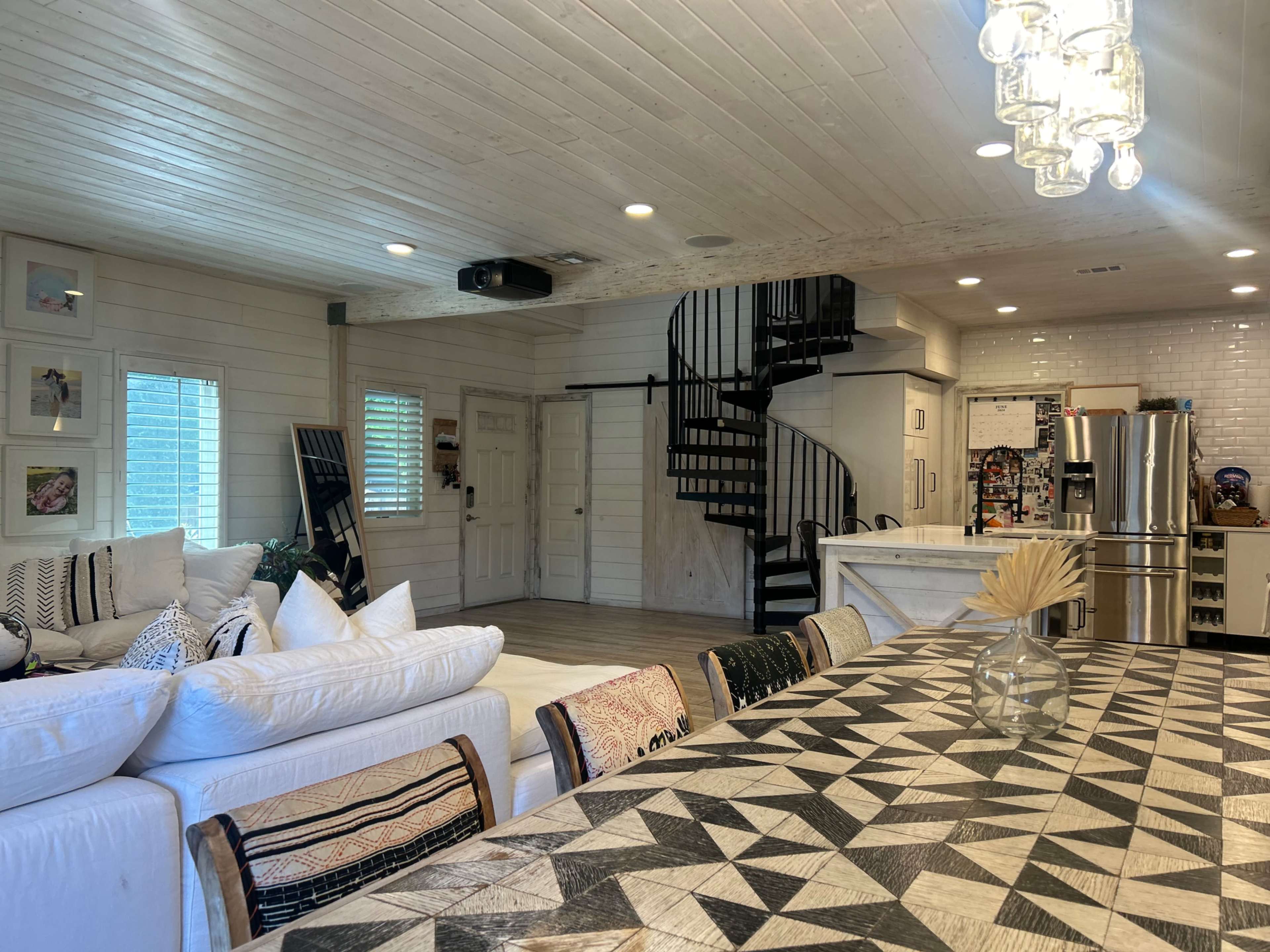 A stylish living area with a spiral staircase, a large dining table with a geometric pattern, and a comfortable seating arrangement.