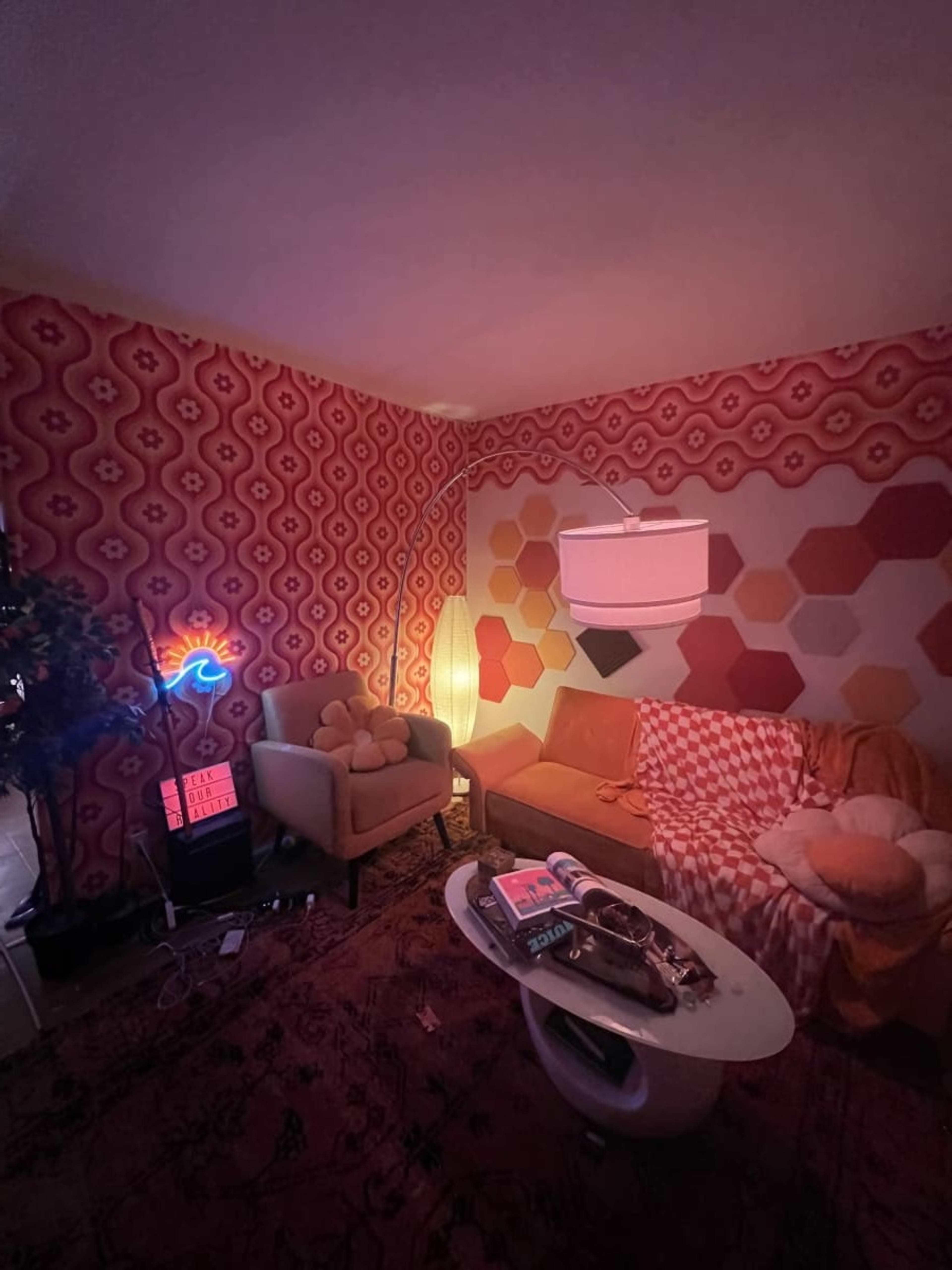 A cozy living room with patterned wallpaper, two couches, a coffee table, and a neon light.