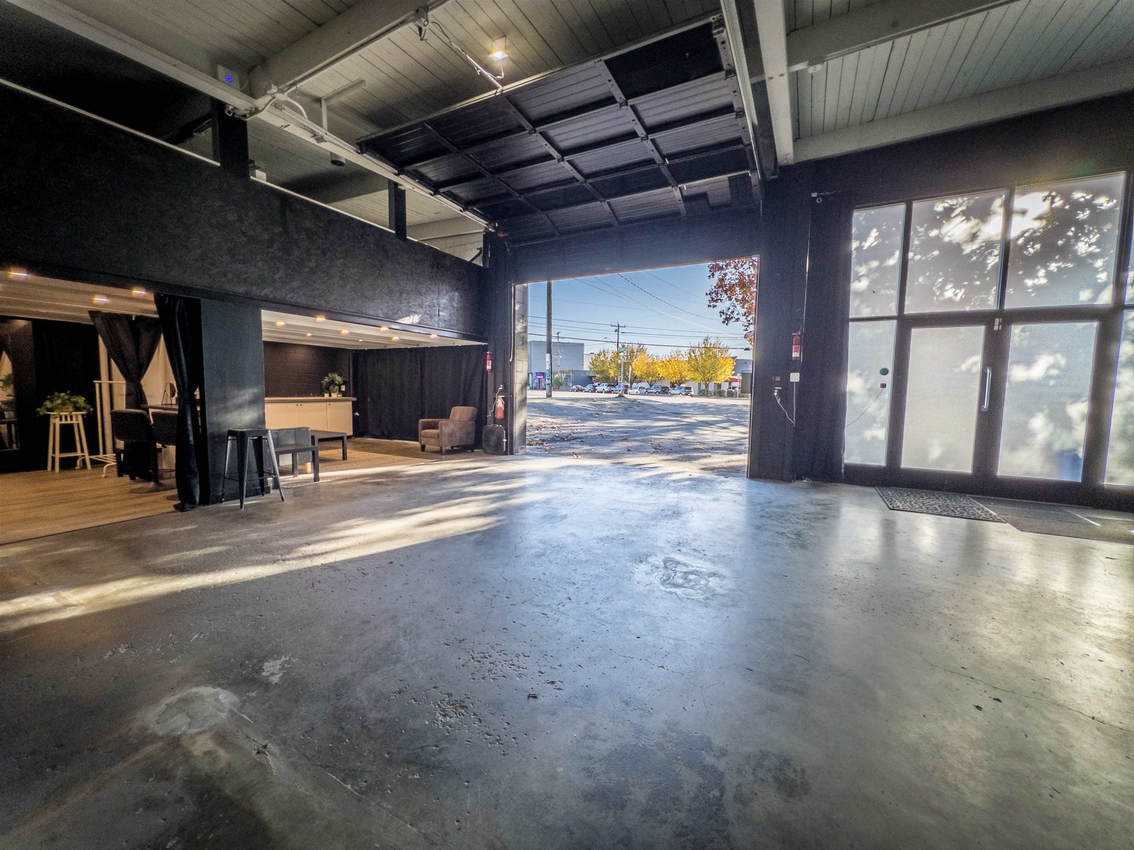 An open interior space with a polished concrete floor and large glass doors leading to an outdoor area.