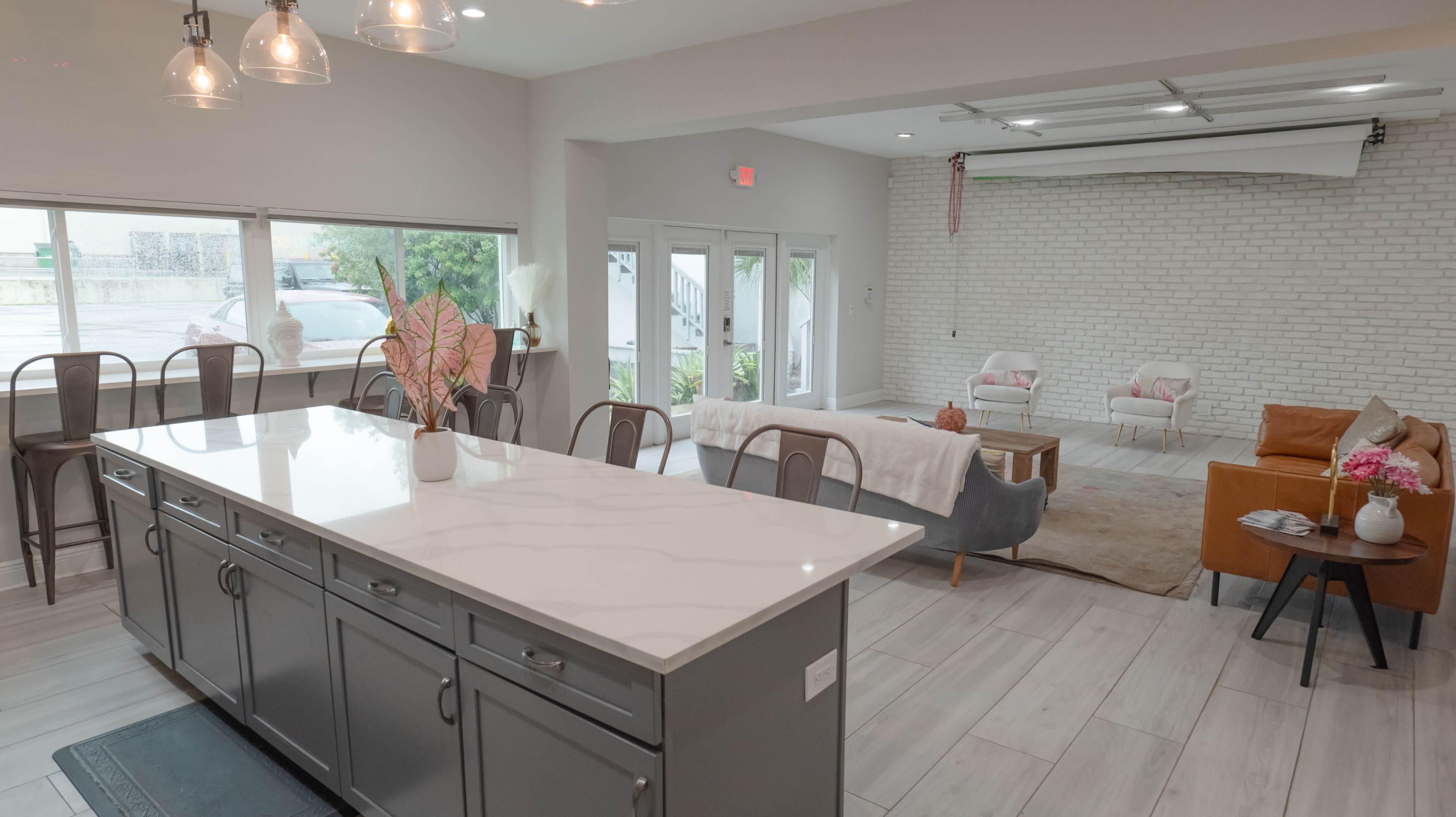 A modern open-concept living space featuring a kitchen island, a seating area, and large windows that provide natural light.