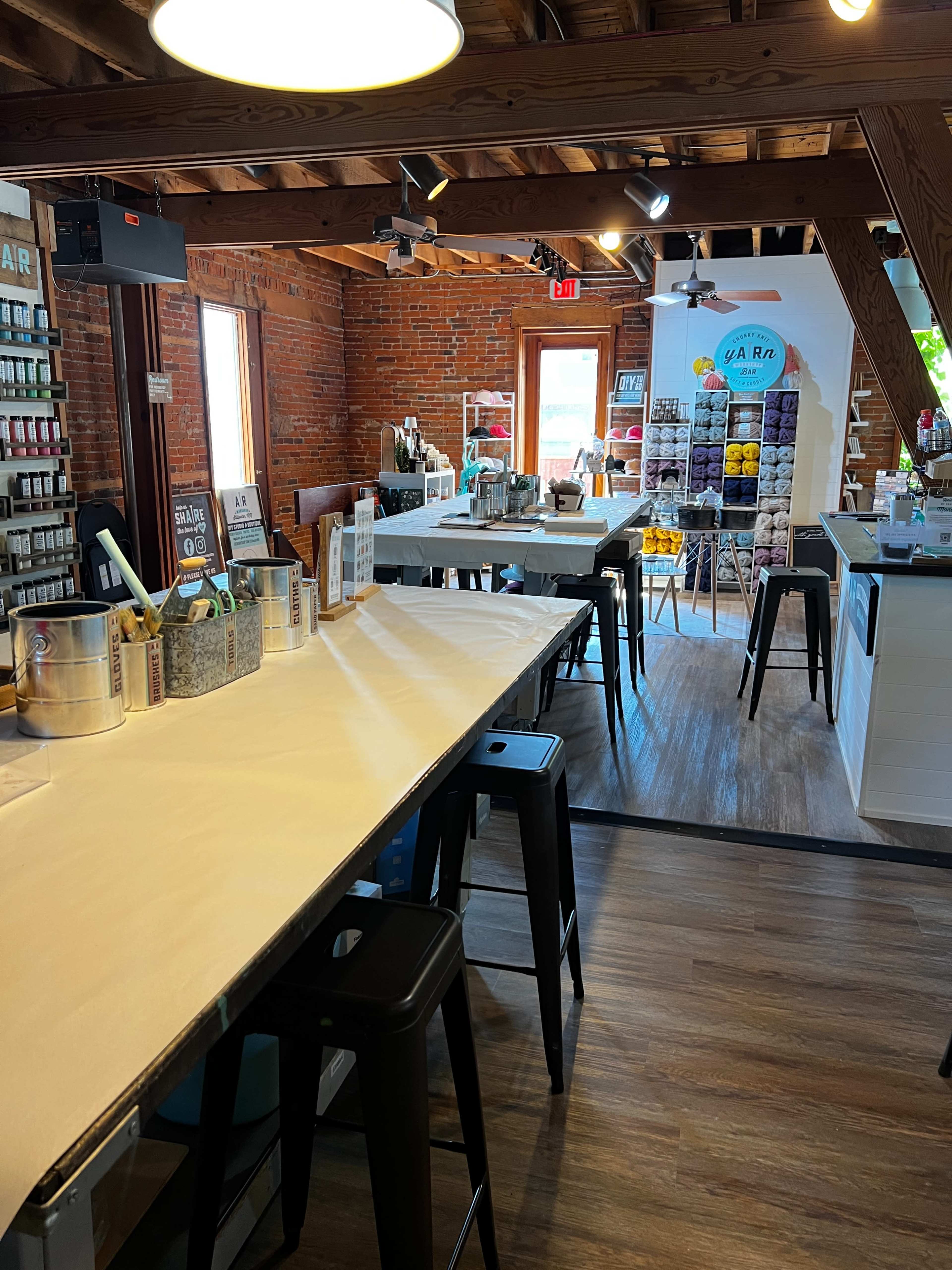 The image shows a modern kitchen or food preparation area with wooden beams, a long countertop, and shelves containing various packaged goods and food items.