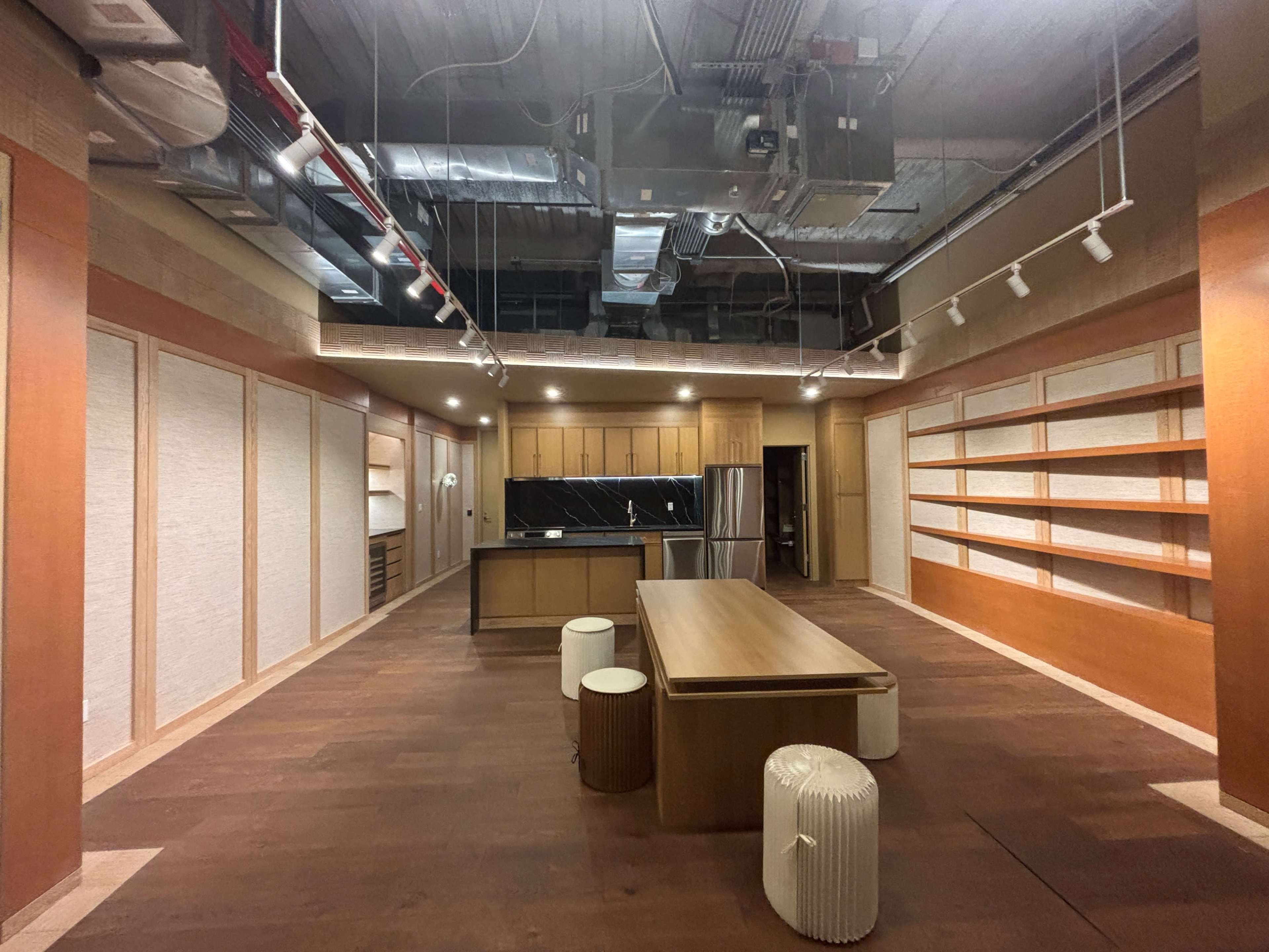 An empty kitchen and dining area features a central wooden table, built-in shelving, and modern appliances.