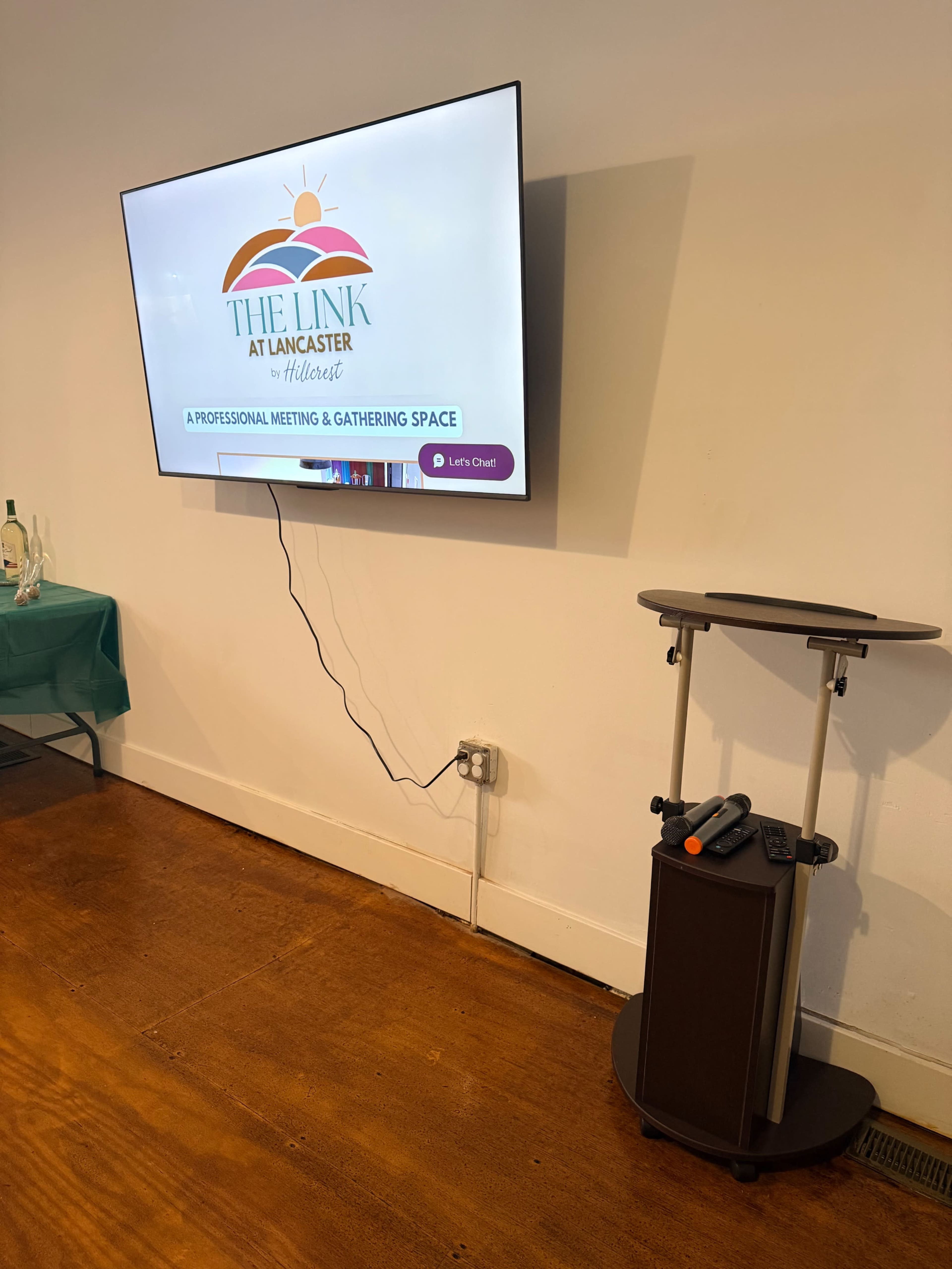 A wall-mounted screen displays information about "The Link at Lancaster," accompanied by a nearby podium featuring a remote control.