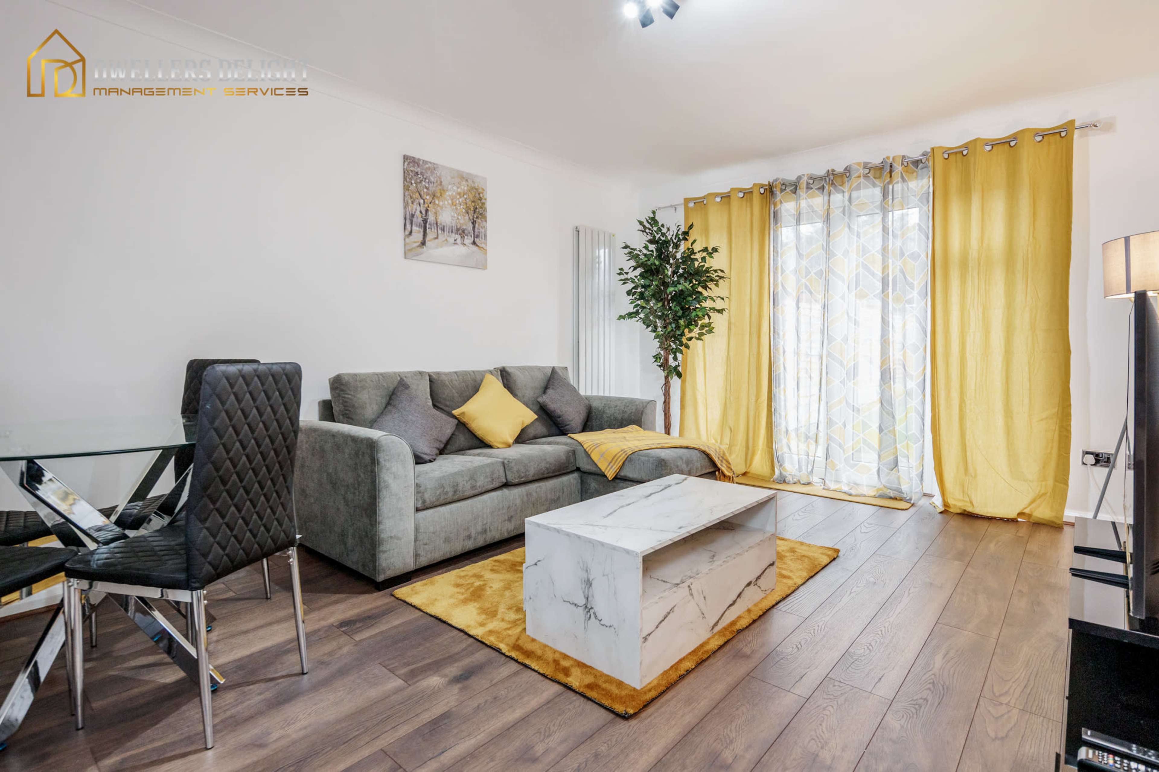 A modern living room with a gray sofa, a marble coffee table, and large yellow curtains.