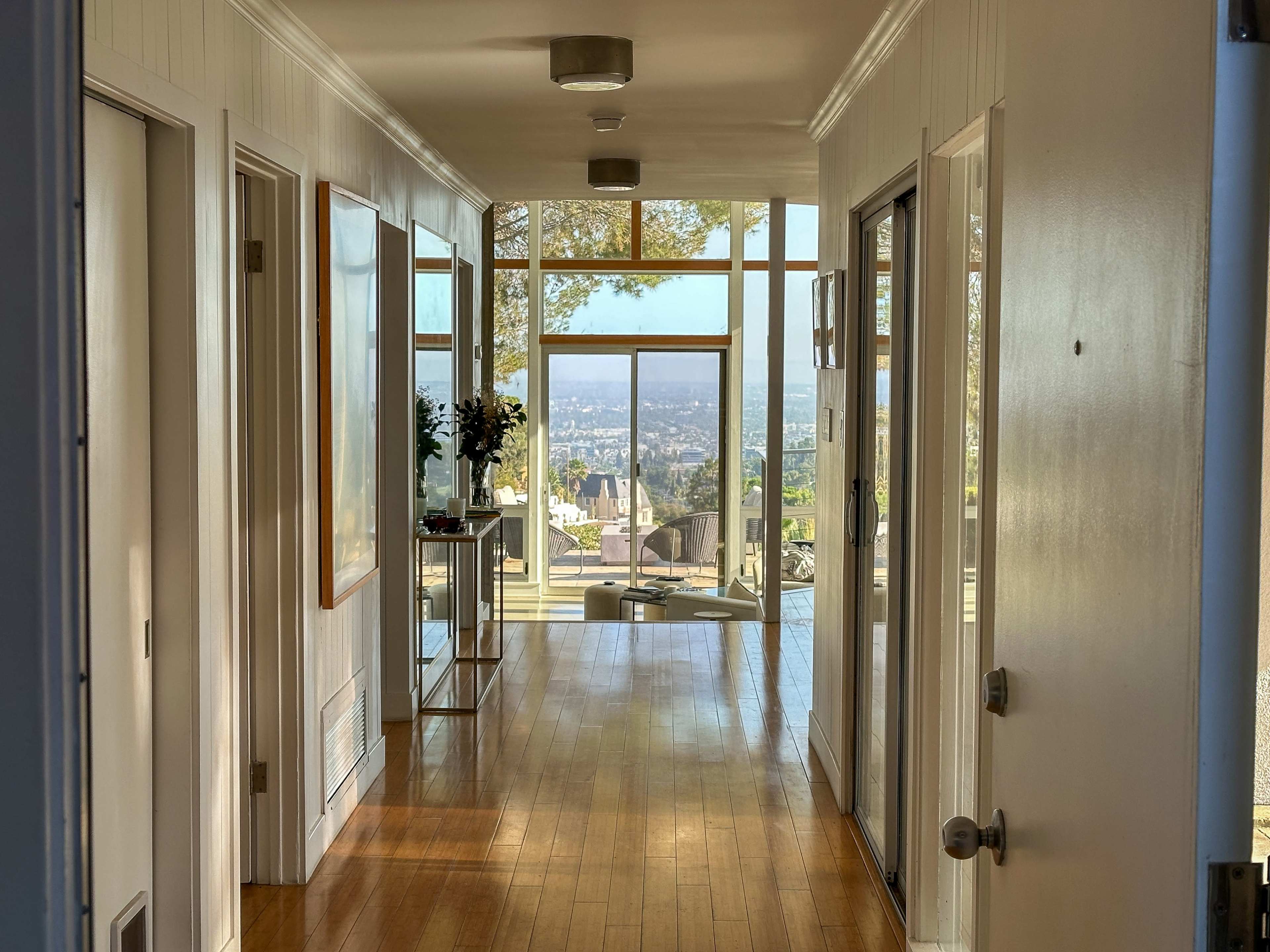 A long hallway leading to large windows with a view of the landscape outside.