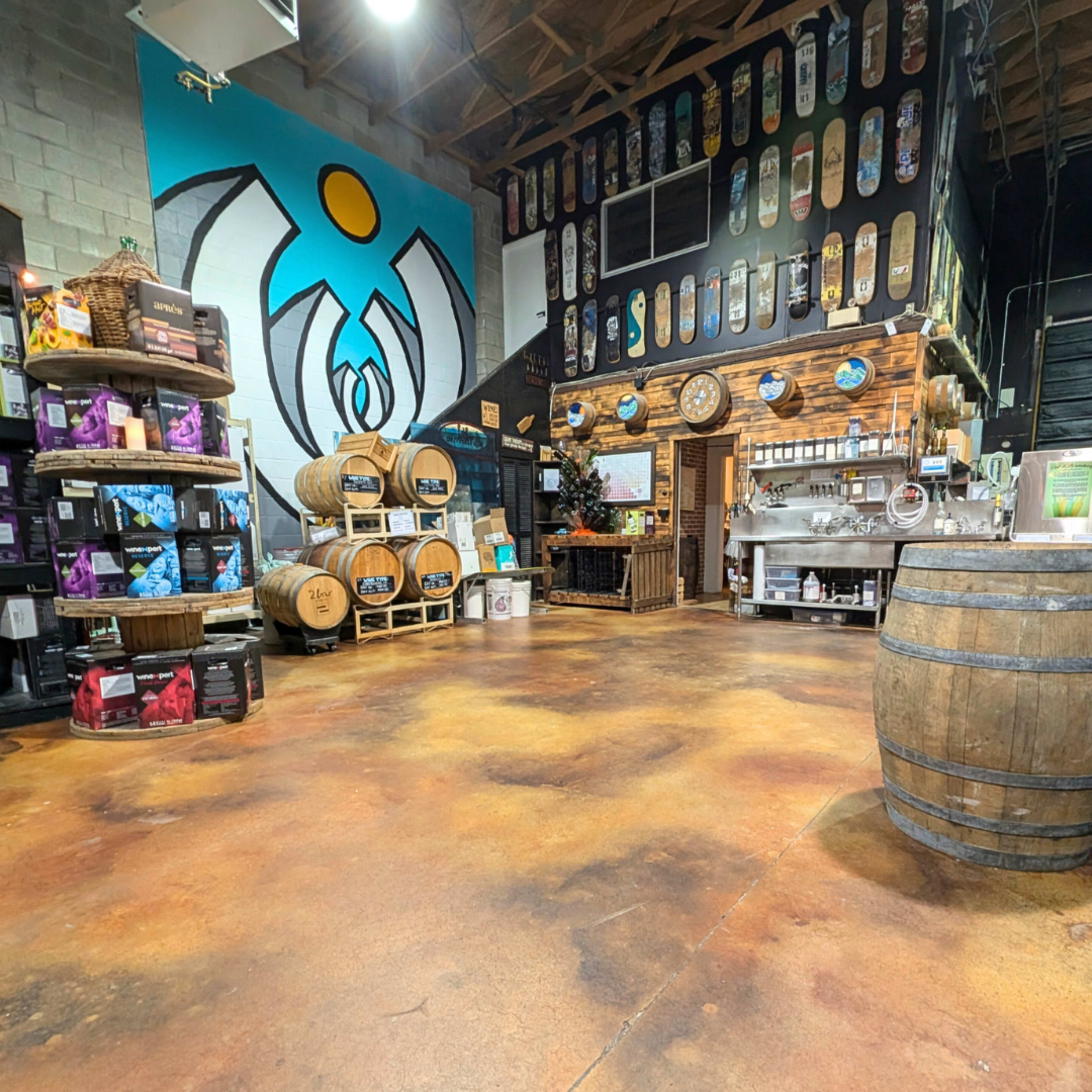 The image shows an interior space featuring a colorful mural, shelves filled with products, wooden barrels, and a serving counter.