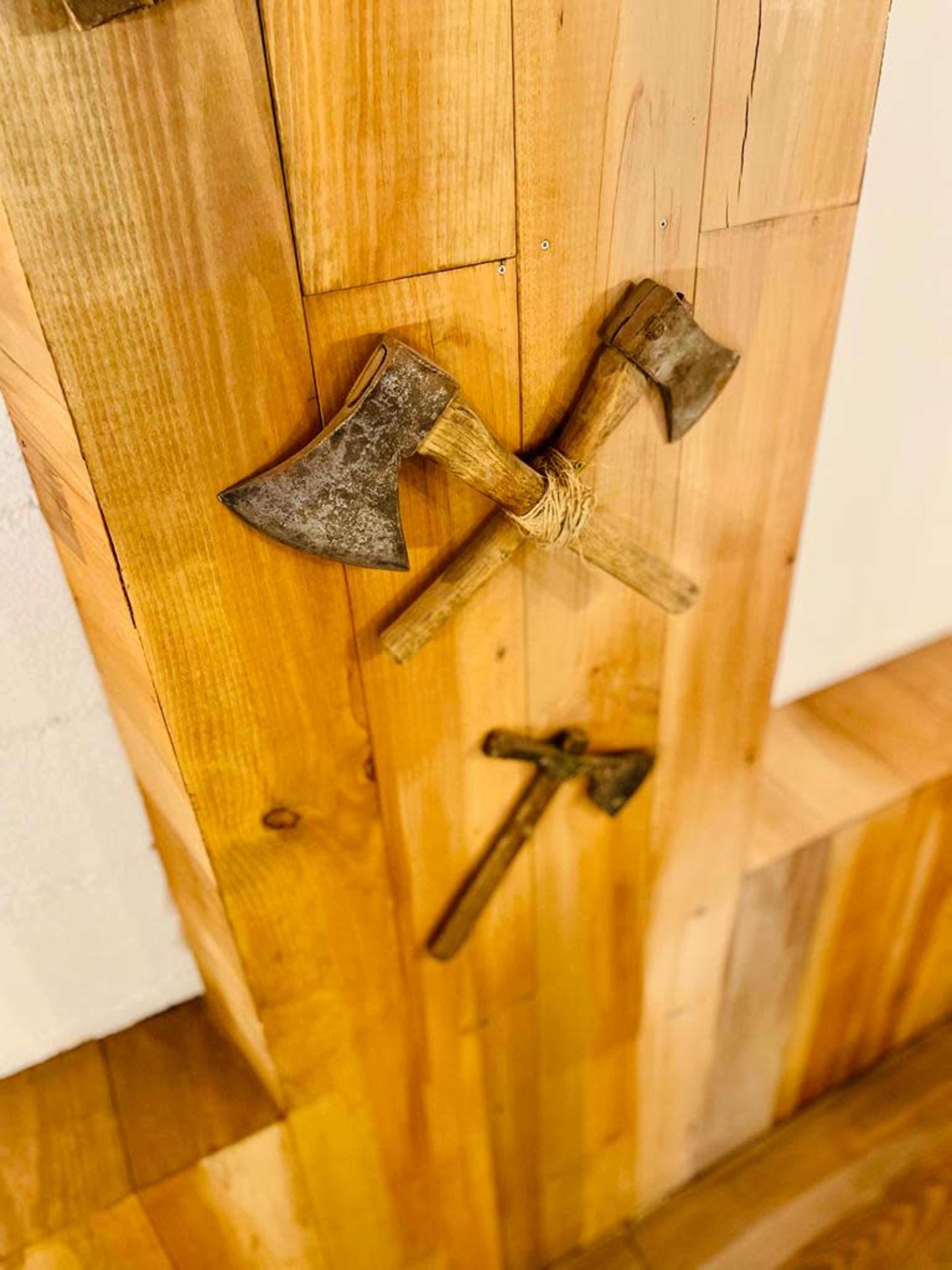 Two crossed axes and a smaller axe mounted on a wooden wall.