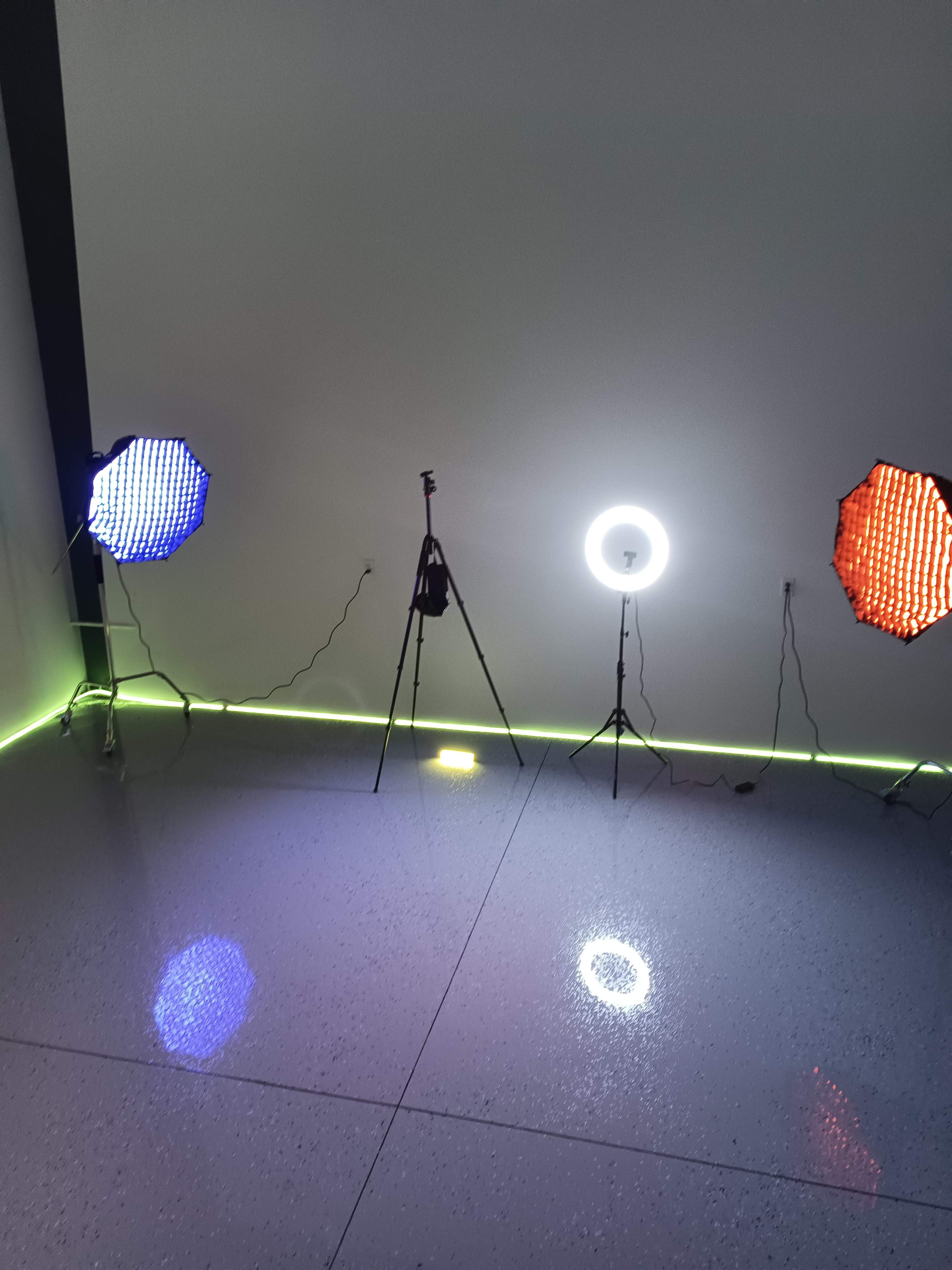 The image shows three lighting setups arranged on a glossy floor, with two colored light sources on the left and right sides and a ring light in the center.