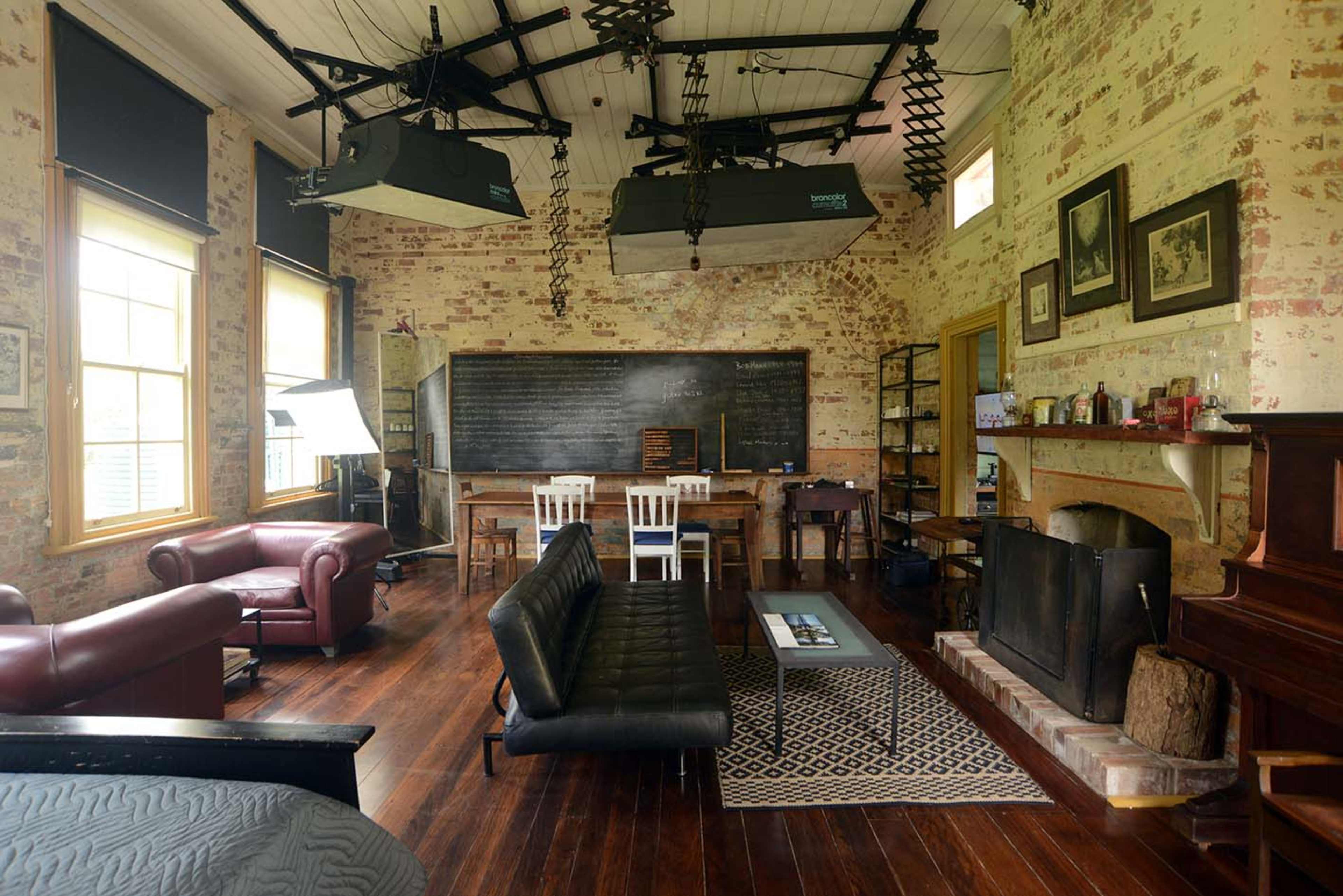 A rustic room with exposed brick walls, a fireplace, various seating arrangements, and a large chalkboard.