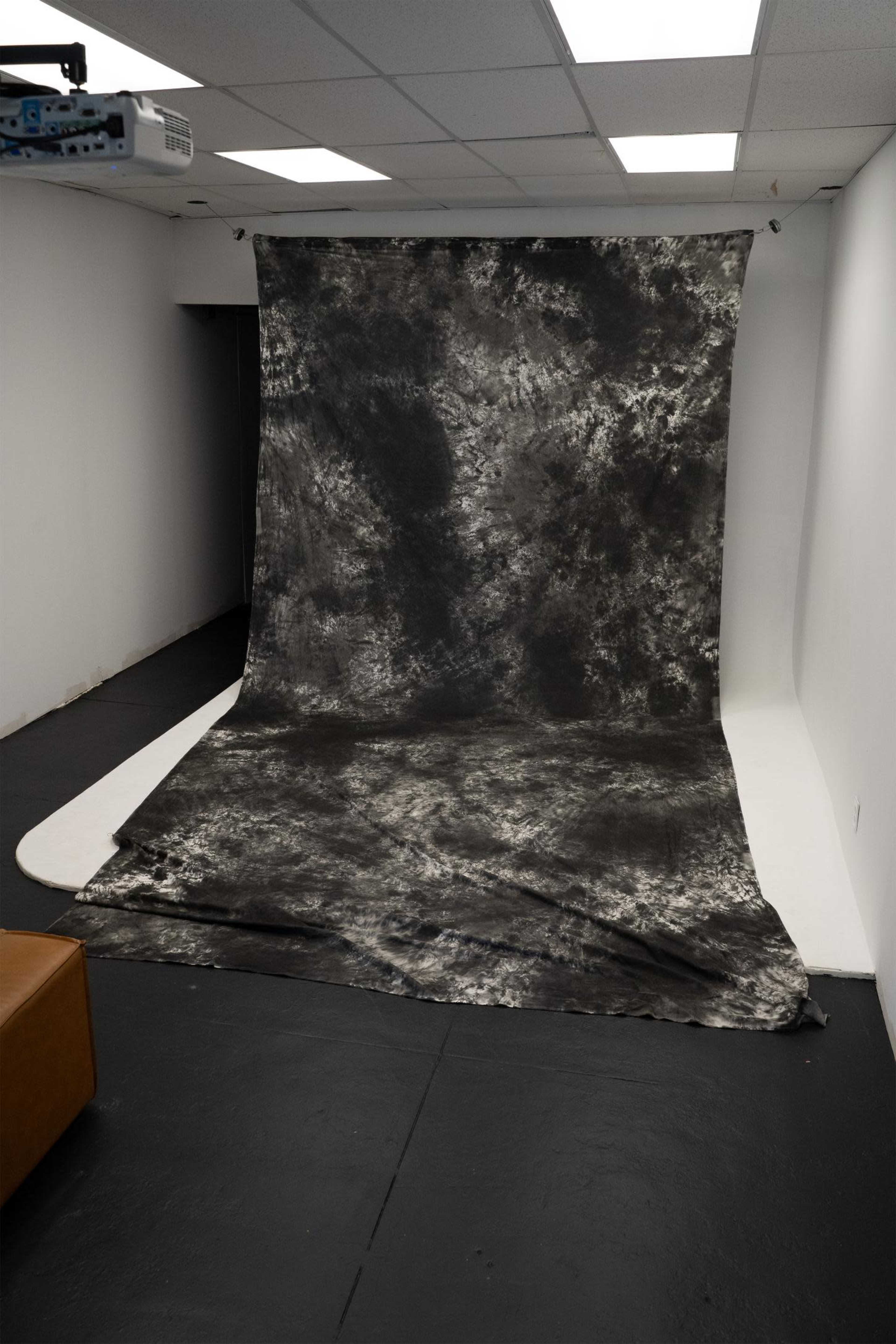 The image shows a photography studio with a large, textured backdrop extending onto the floor.
