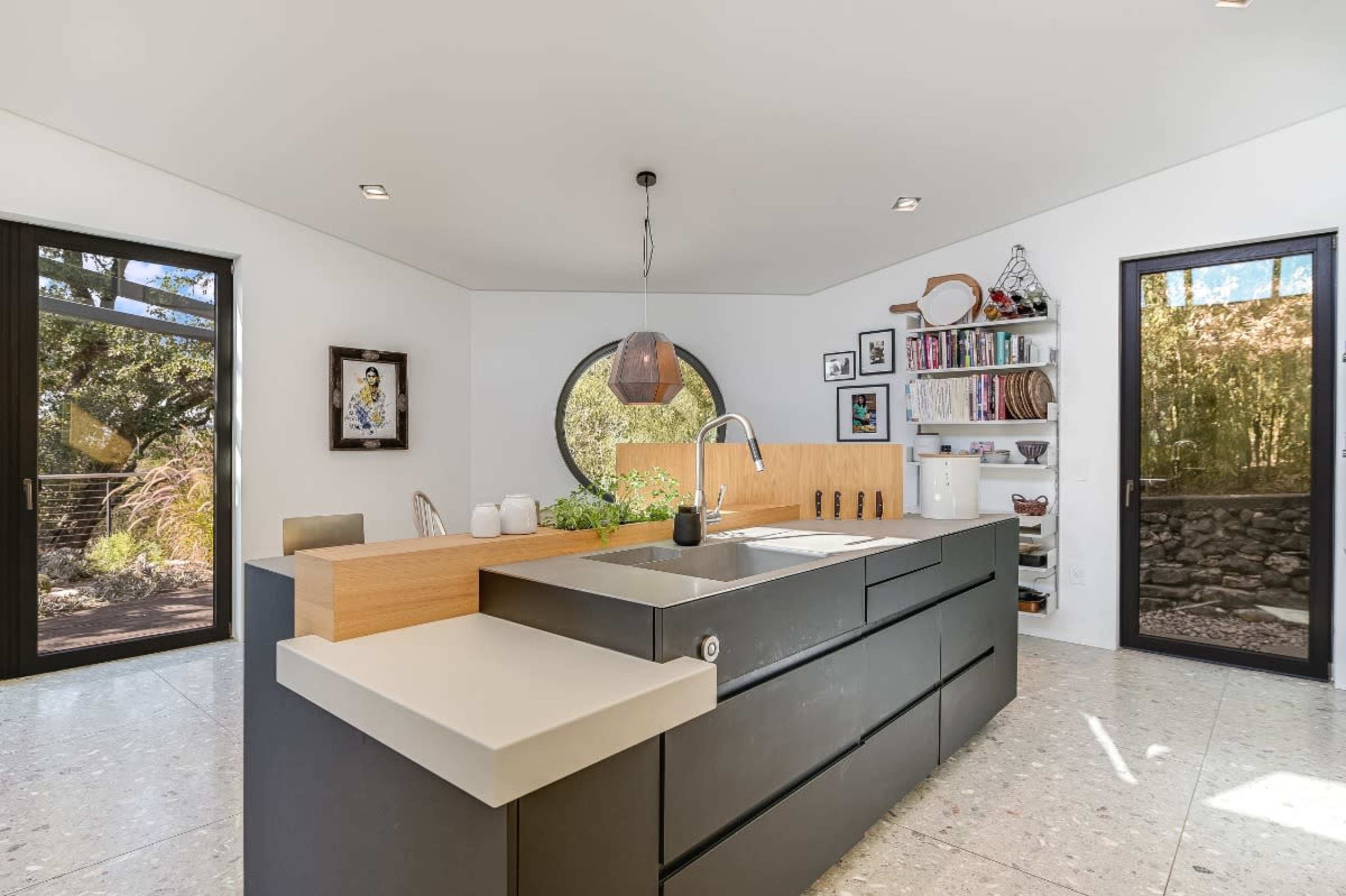 The image showcases a modern kitchen with a central island, large windows, and a mix of dark cabinetry and light countertops.