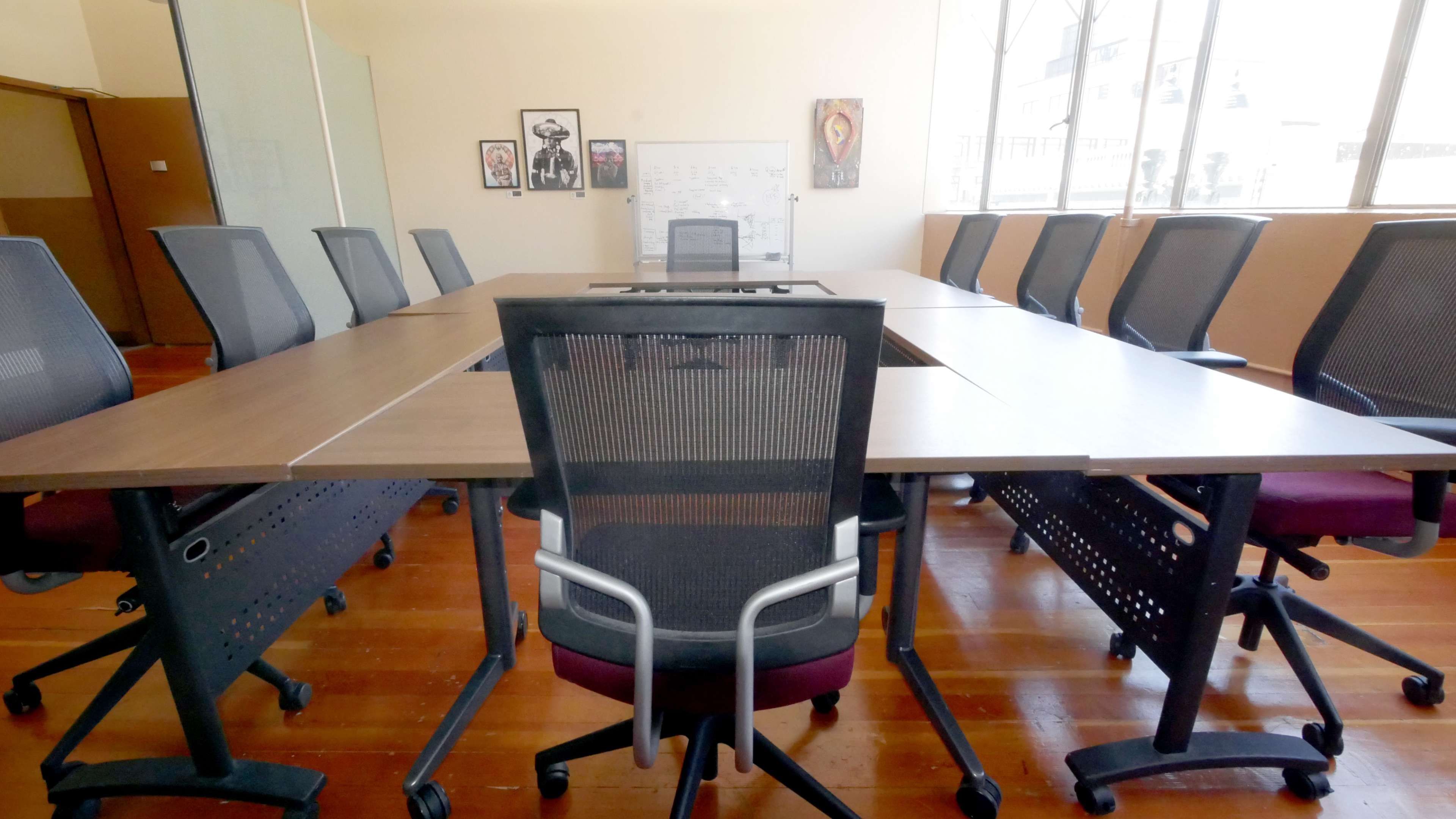 A conference room features a large table surrounded by several ergonomic chairs and large windows.
