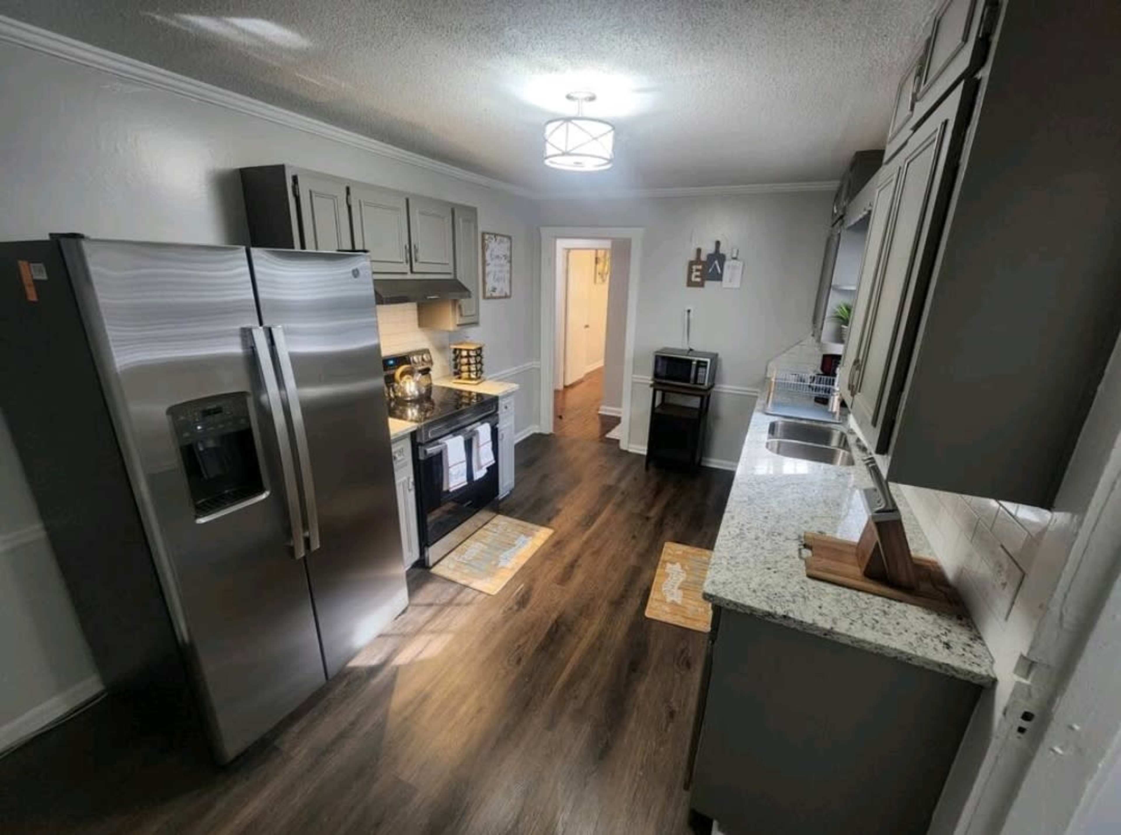 The image shows a modern kitchen with stainless steel appliances, gray cabinetry, and a granite countertop.