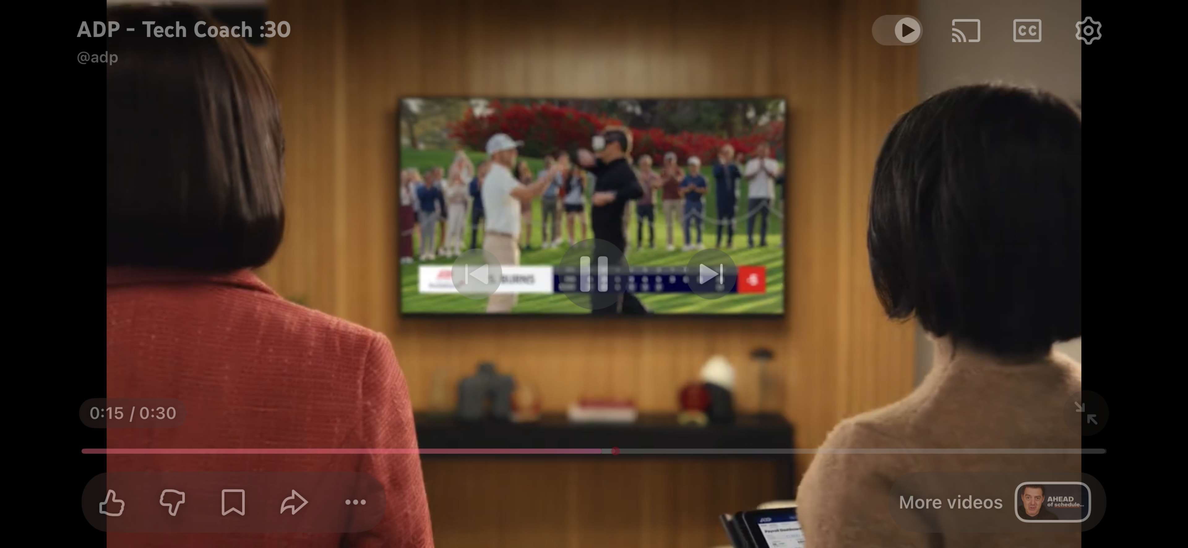Two women watch a golfing event on a television in a well-decorated room.
