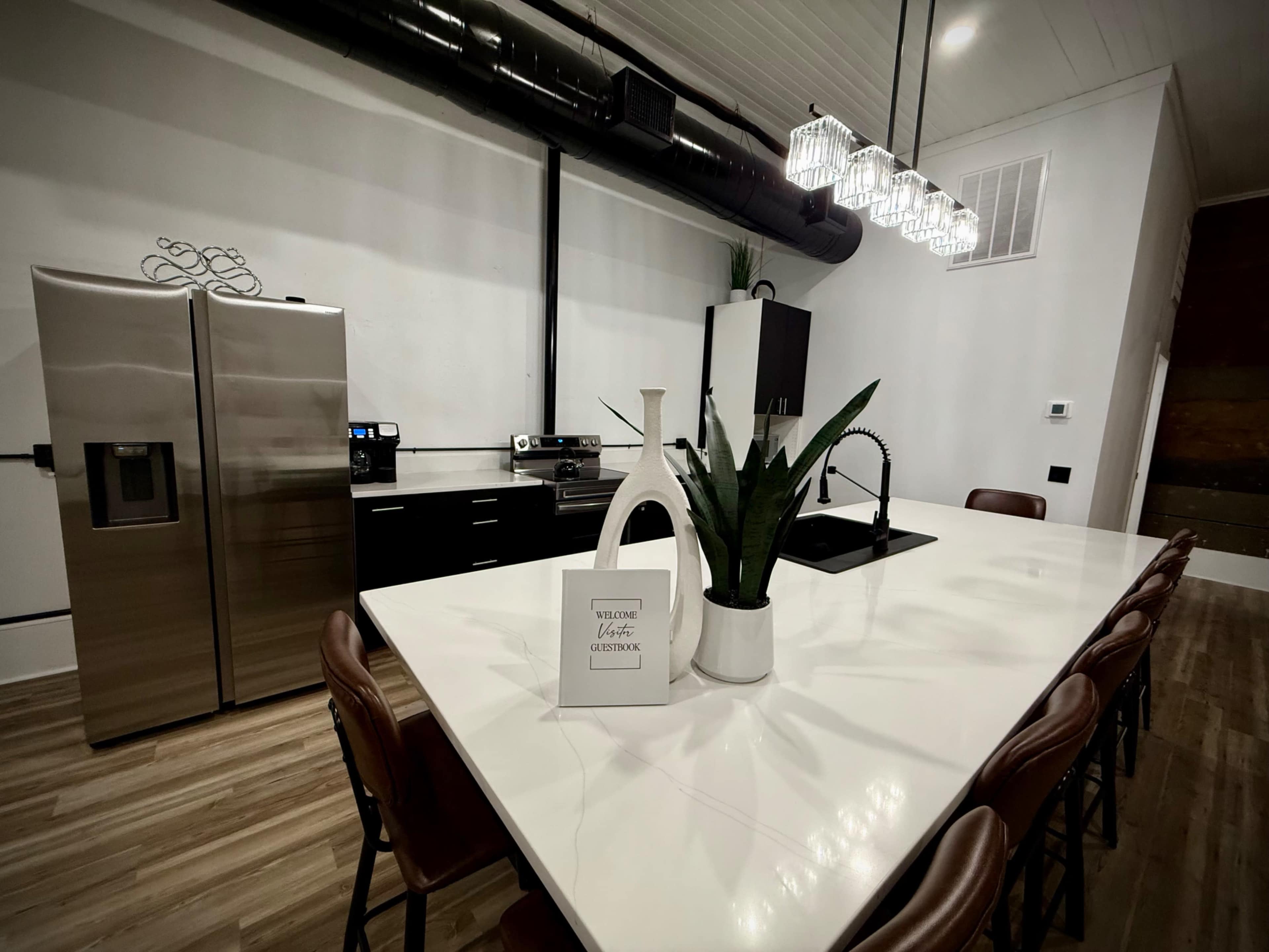 A modern kitchen features a large white island, stainless steel appliances, and minimalistic decor.