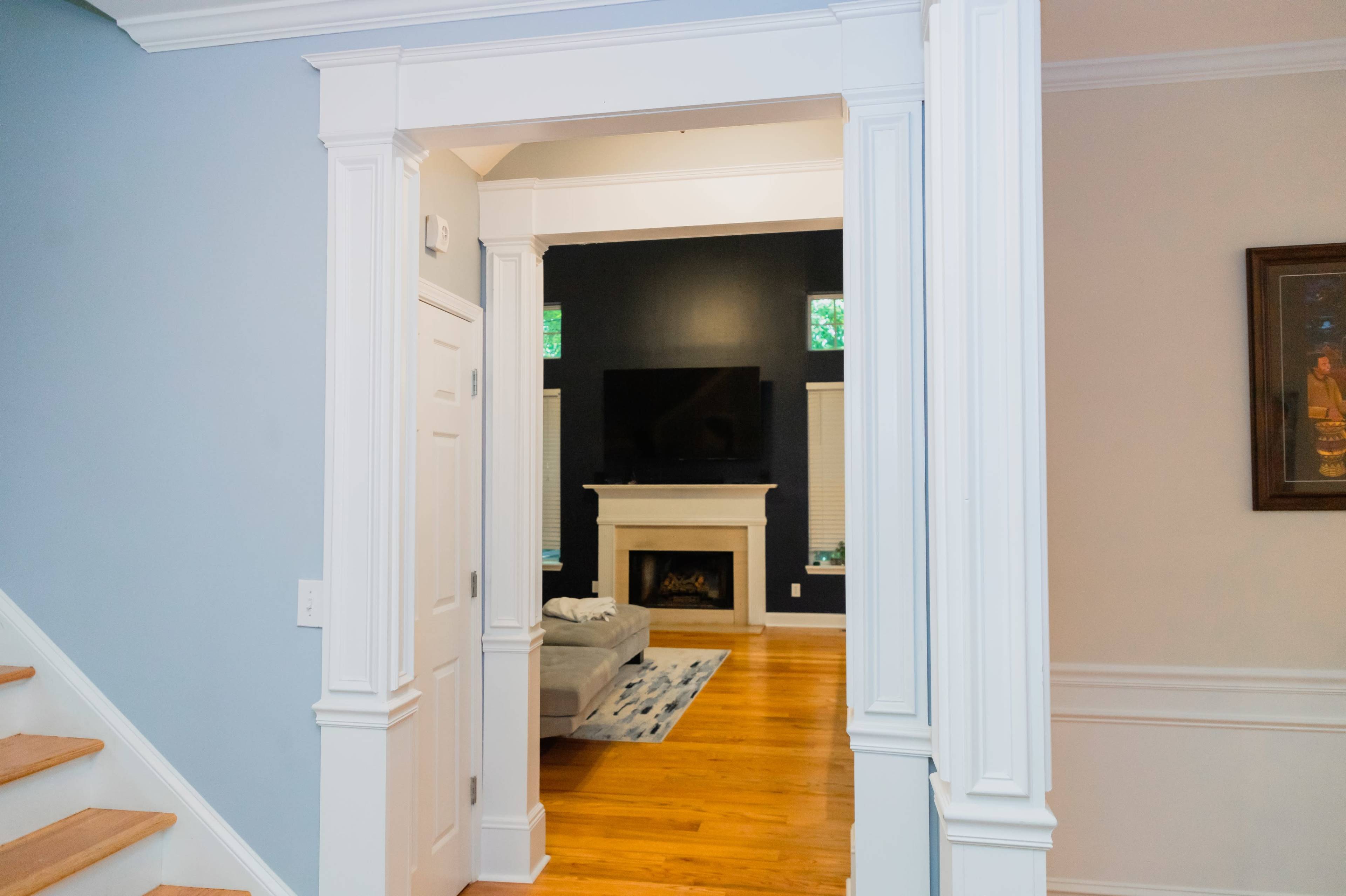 A view of a foyer leading into a living room with a fireplace and a television mounted on the wall.