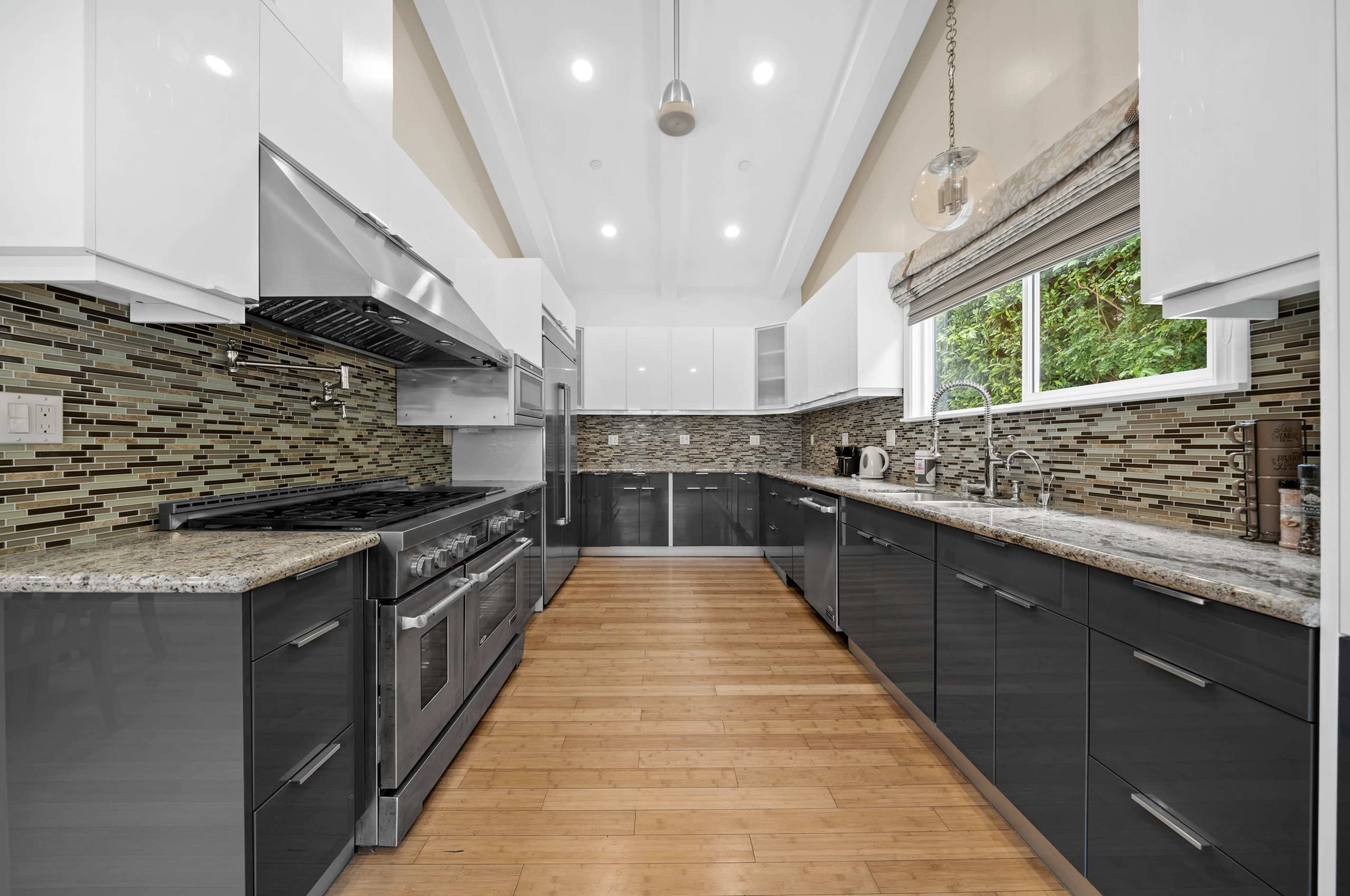 The kitchen features sleek cabinets, a large stainless steel oven, and a modern backsplash with a blend of tiles.