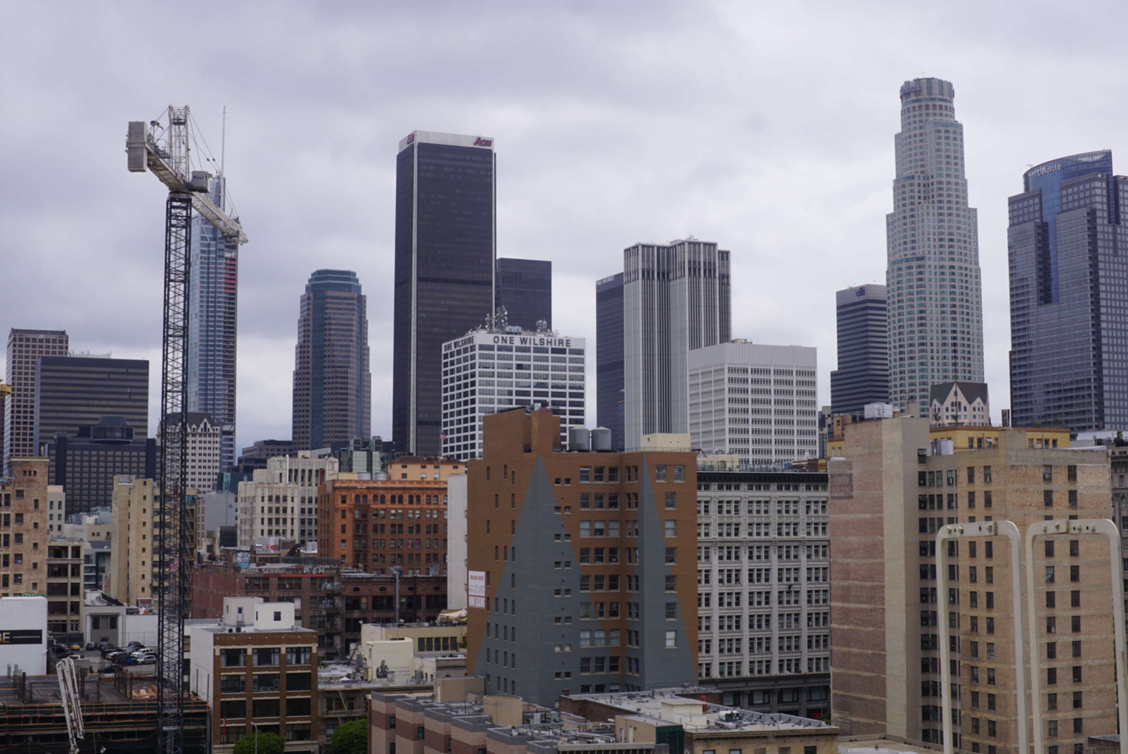 The image shows a view of a city skyline with various high-rise buildings and a construction crane in the foreground.