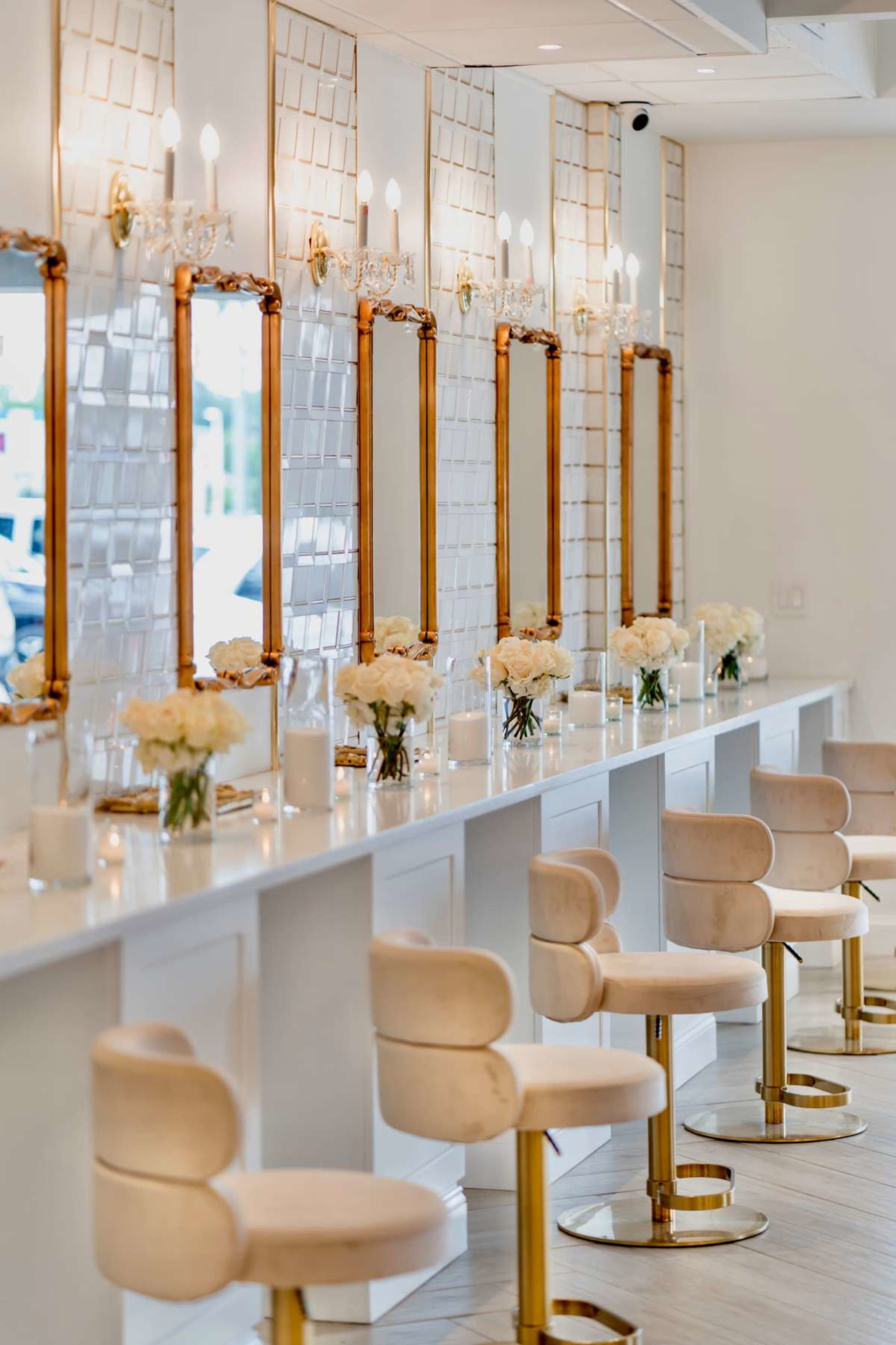 The image shows a grooming salon with a row of illuminated mirrors and elegant seating along a white countertop.