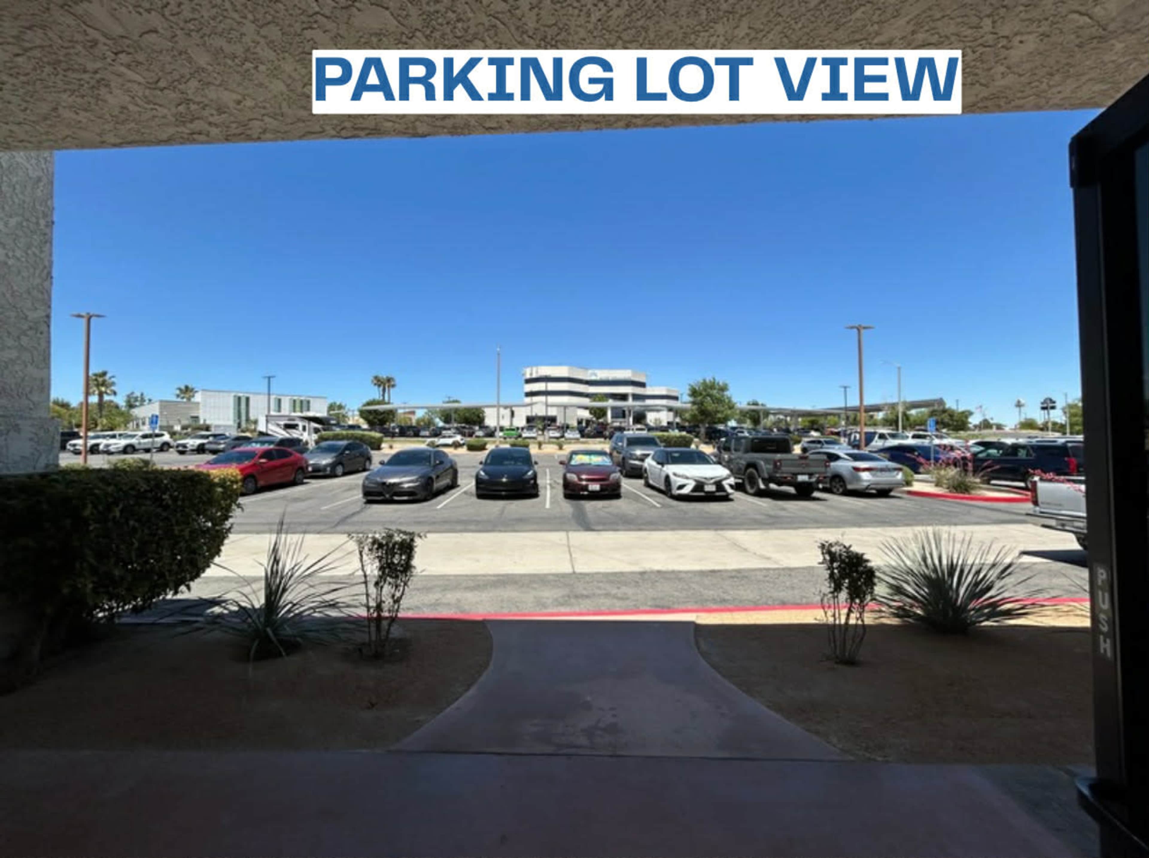 The image shows a view of a parking lot with several parked cars and a building in the background.