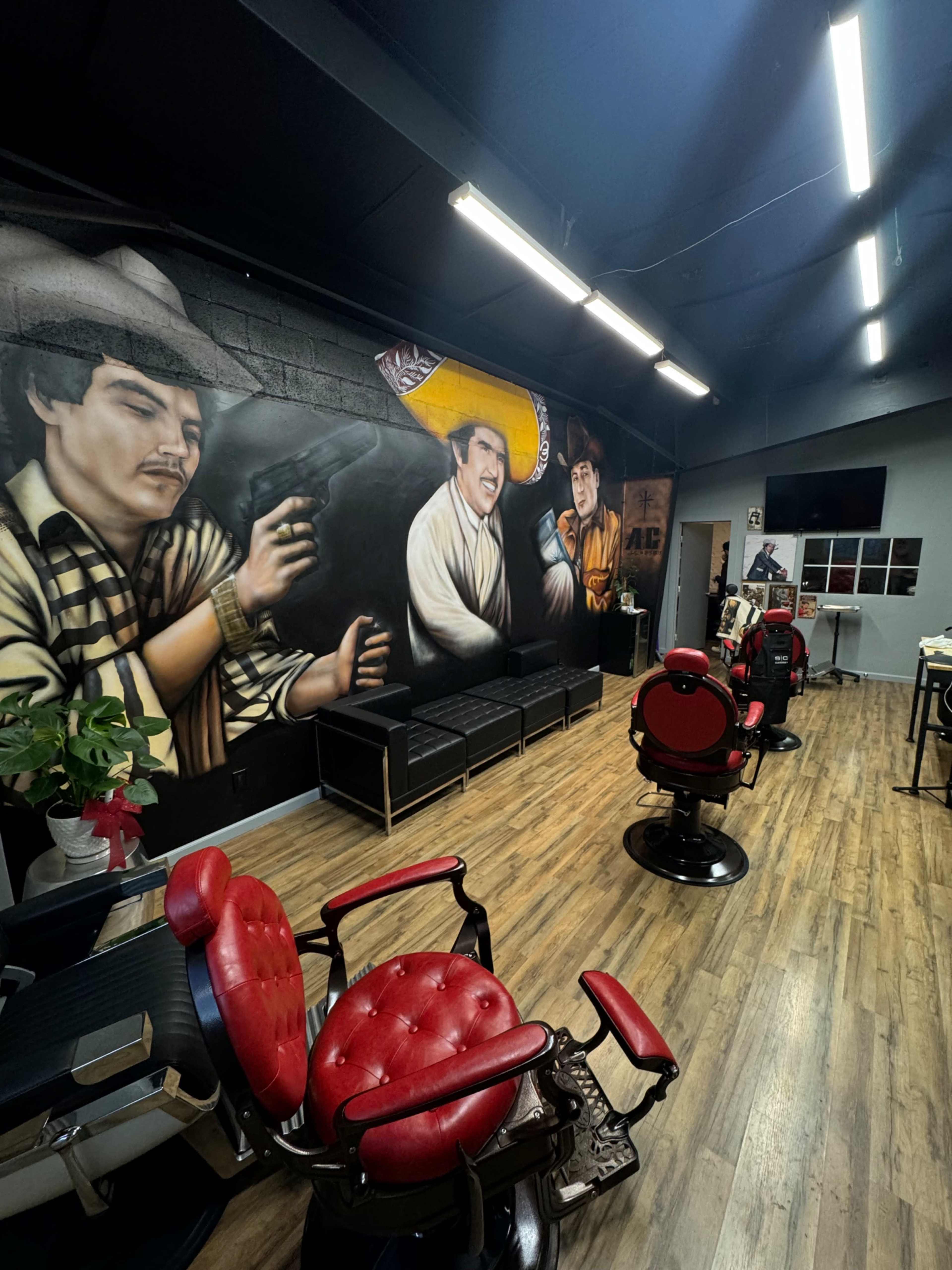 The image shows a modern barbershop interior featuring several barber chairs, a mural on the wall depicting characters, and a reception area with a few black sofas.