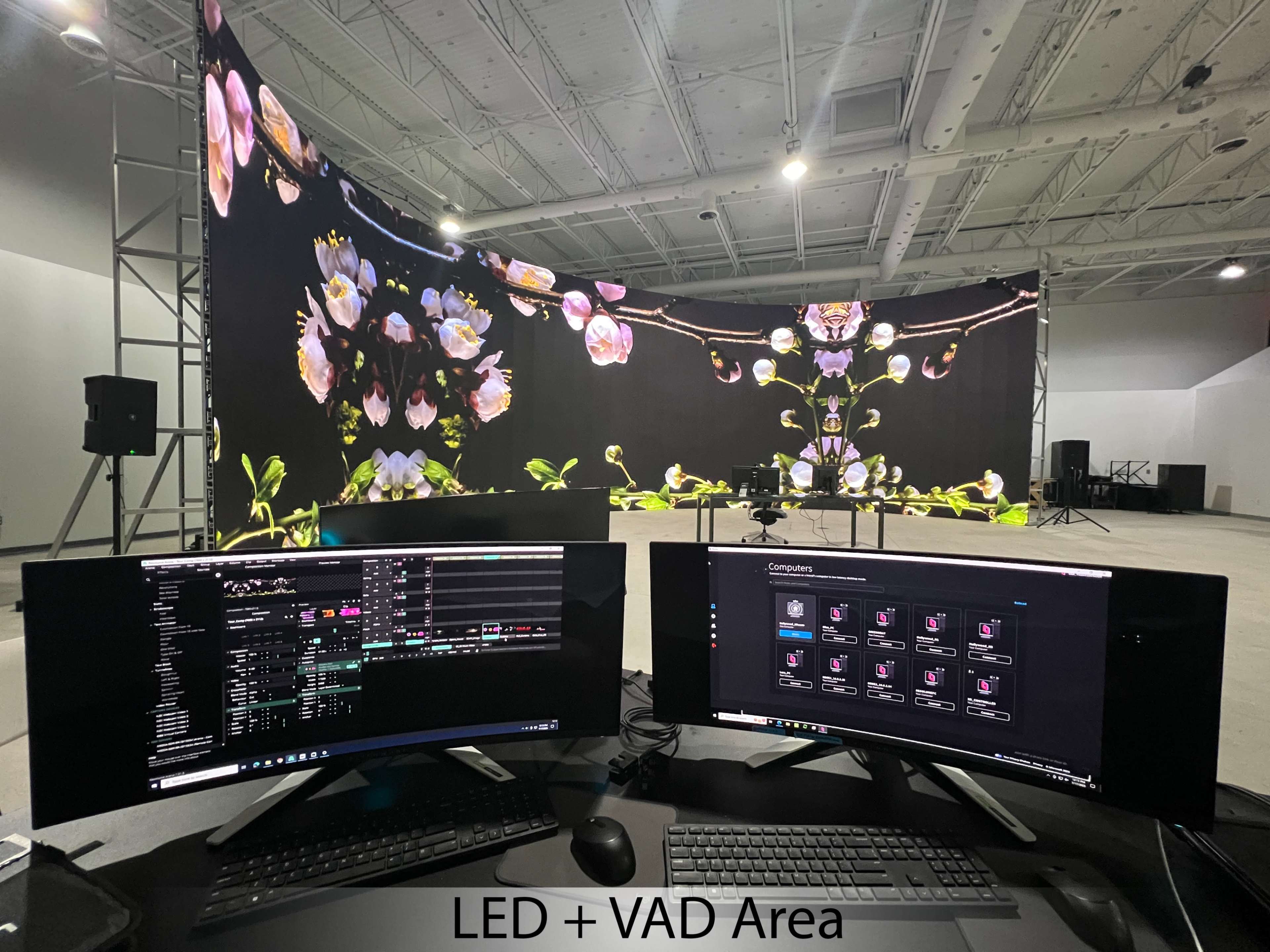 A setup featuring two curved computer monitors displaying software for managing an LED and video area, with a large floral backdrop on a stage behind them.