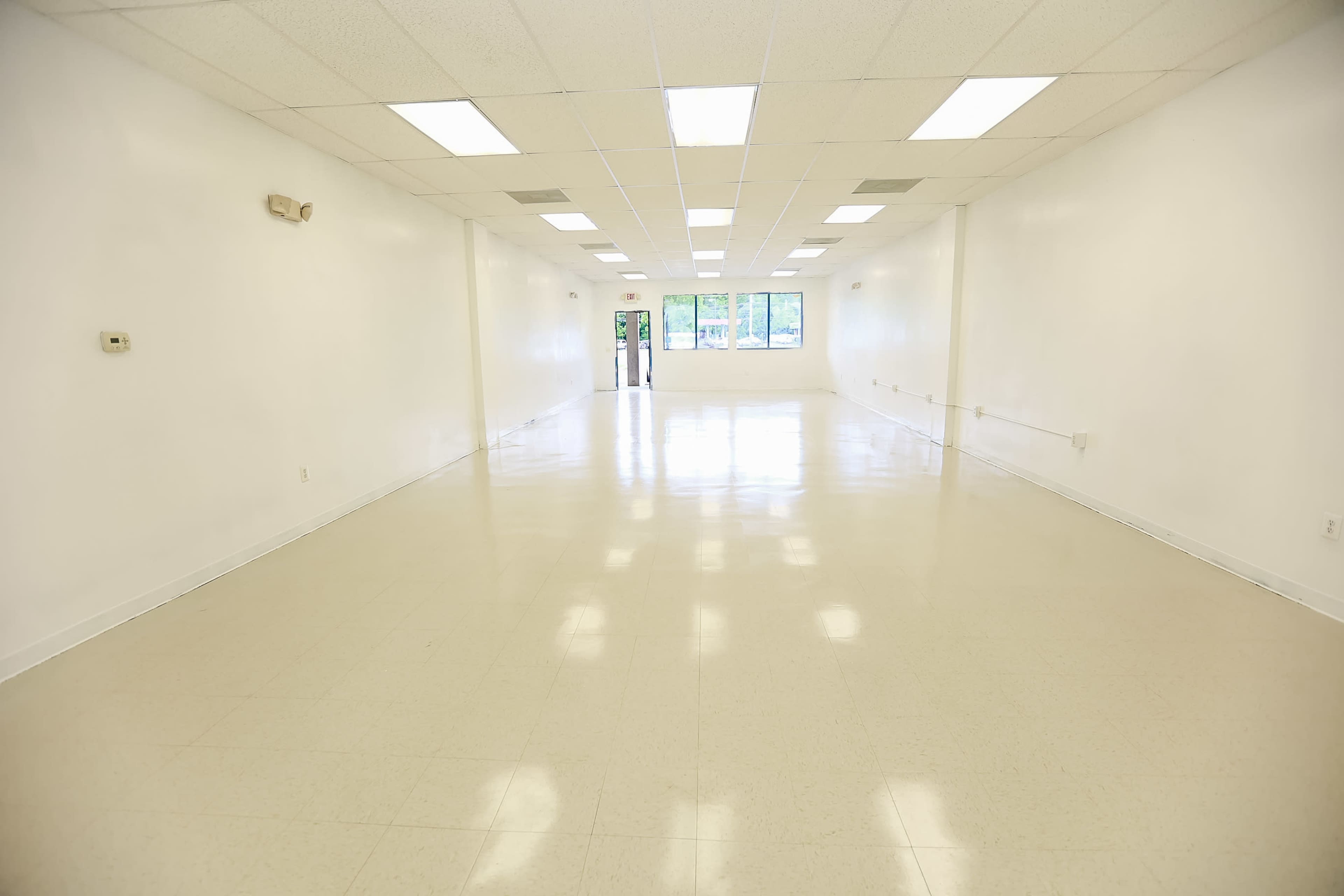 A large, empty, well-lit room with white walls and a glossy floor.