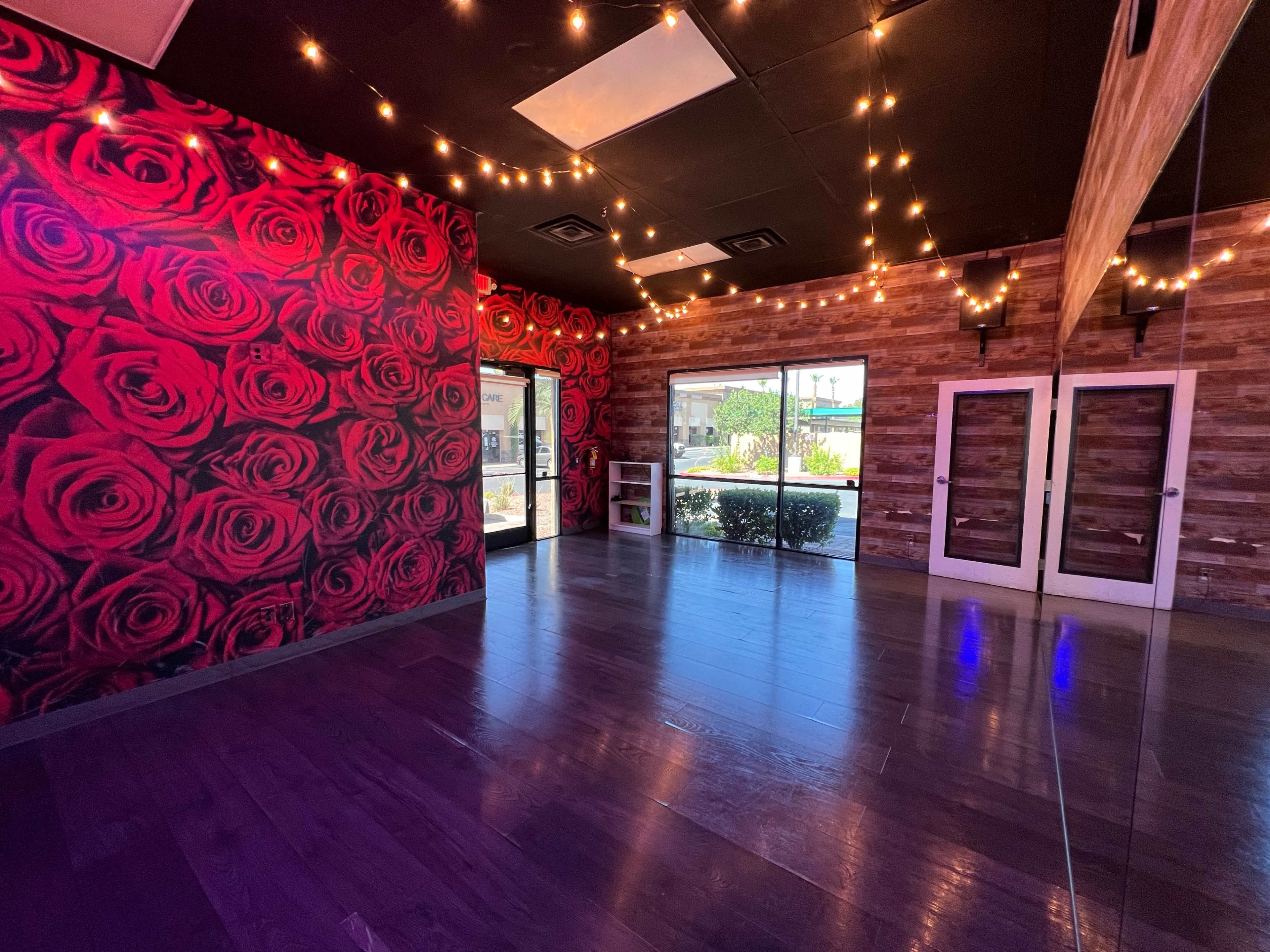 The room features a vibrant rose-patterned wall and wooden accents, illuminated by string lights.