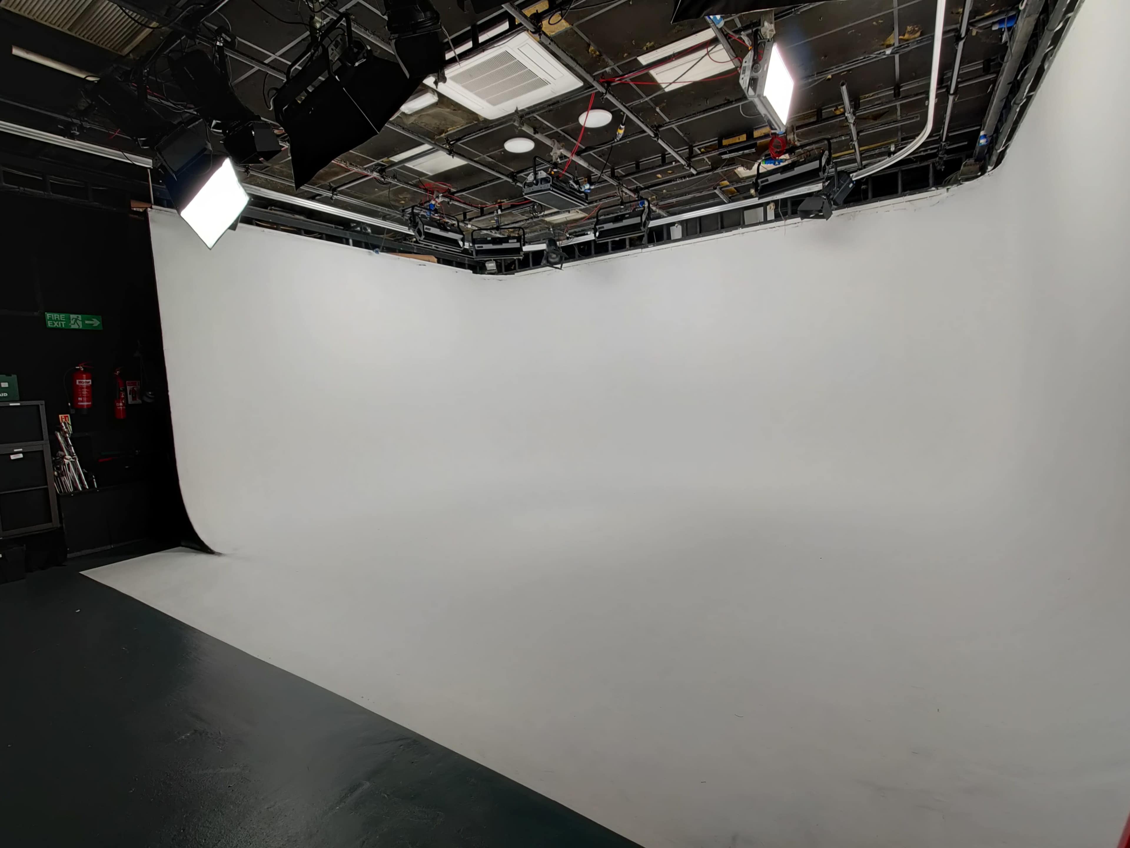 A studio space with a seamless white backdrop and overhead lighting setup.